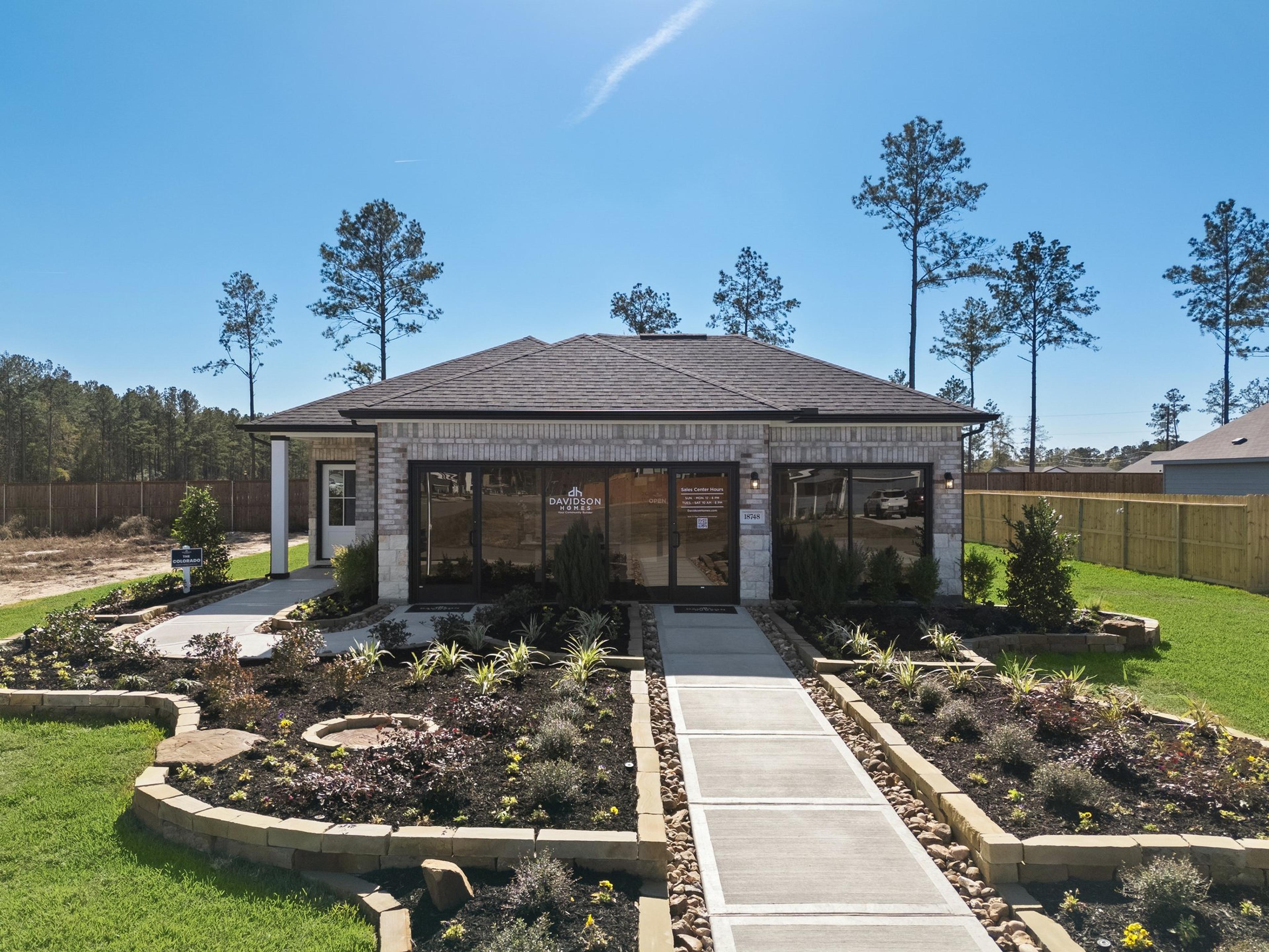 Davidson Homes sales center at Spring Branch Crossing in Conroe, Texas, featuring a landscaped walkway and brick exterior.
