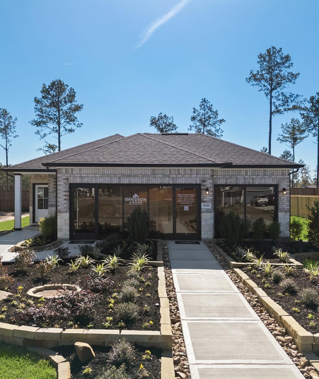 Davidson Homes sales center at Spring Branch Crossing in Conroe, Texas, featuring a landscaped walkway and brick exterior.