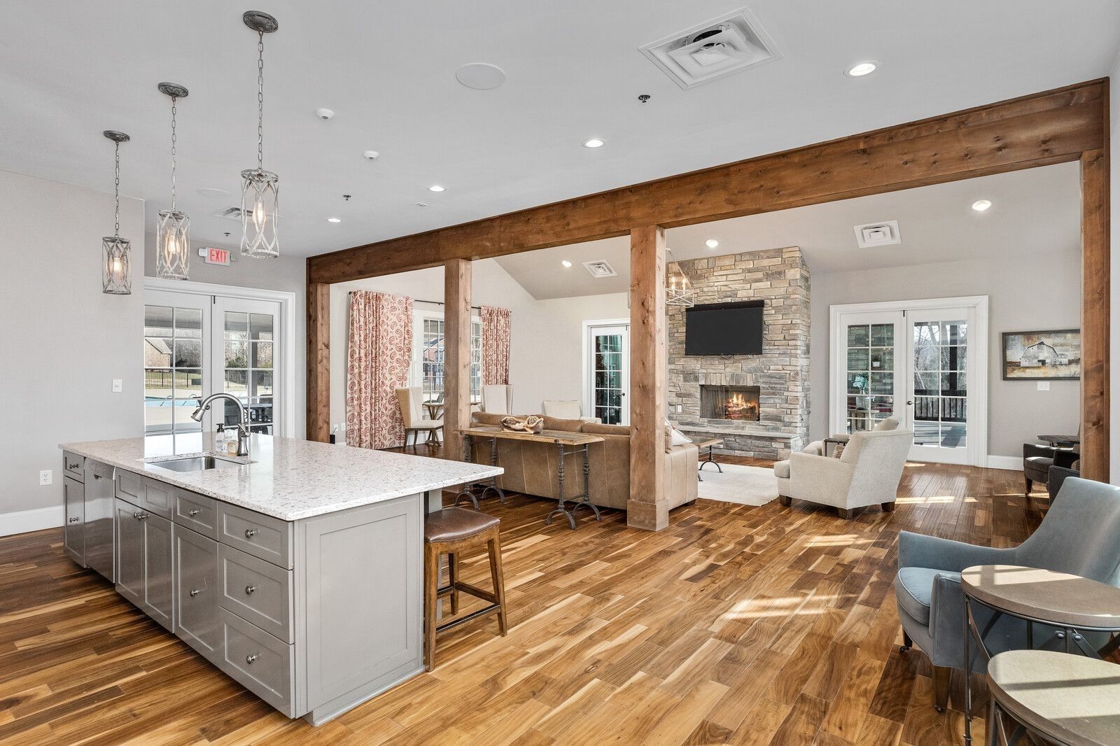 Spacious open living area with quartz island kitchen, wooden beams, stone fireplace, and leather seating in Davidson Homes Ridgeport, Gallatin, TN
