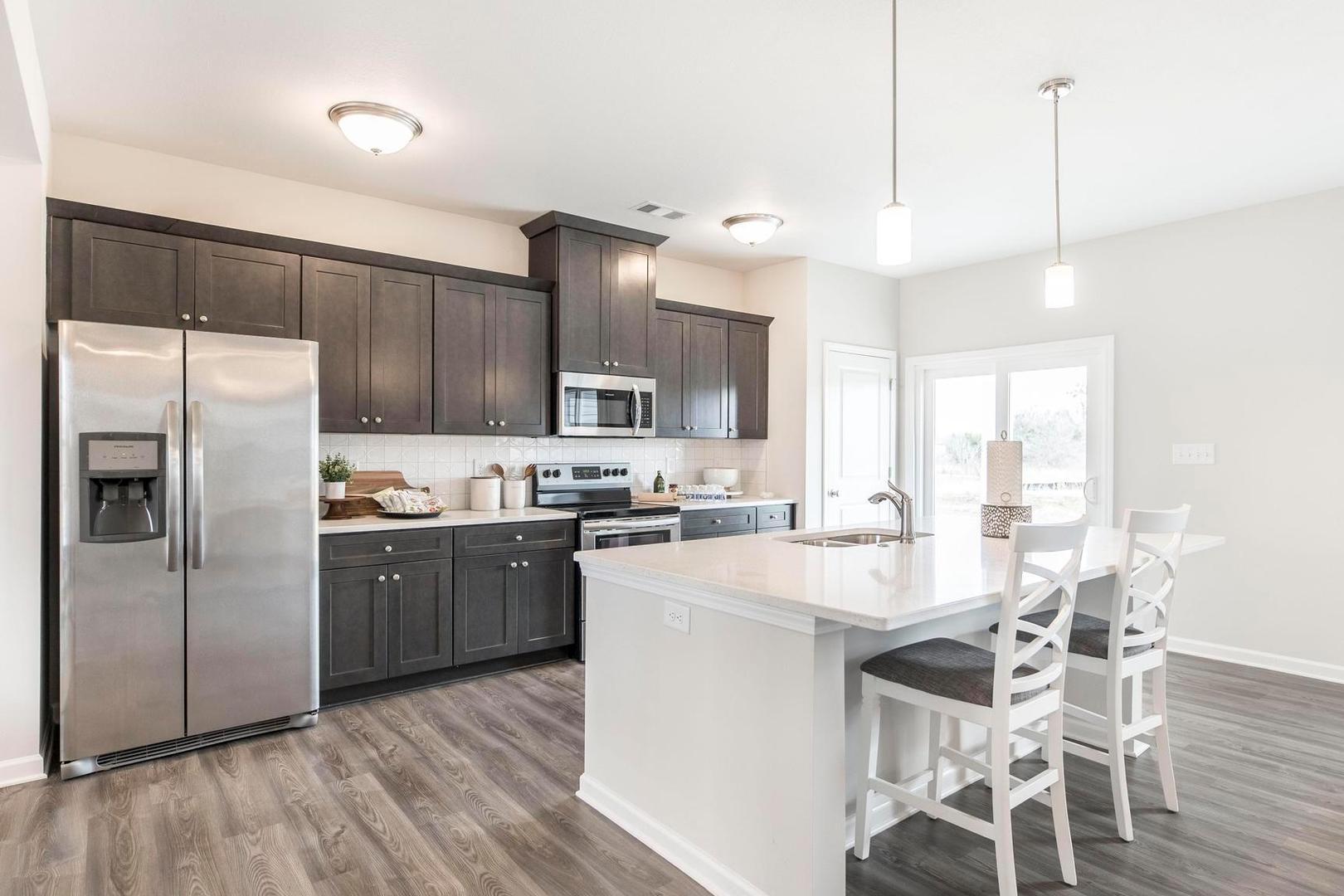 Modern kitchen with dark shaker cabinets, stainless appliances, white island and bar stools at Cape Reserve in Donahue Ridge, Auburn AL