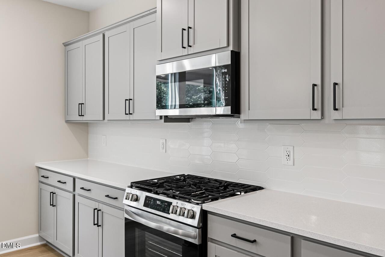 Modern kitchen with gray cabinets, quartz countertops, and gas range in The Chestnut floor plan, Montrose, Aberdeen, NC.