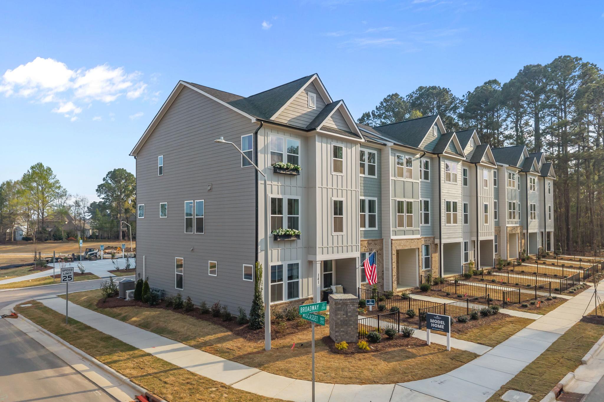 Row of modern townhomes at Camden Park in Knightdale NC with gabled roofs, flower boxes and pine landscaping