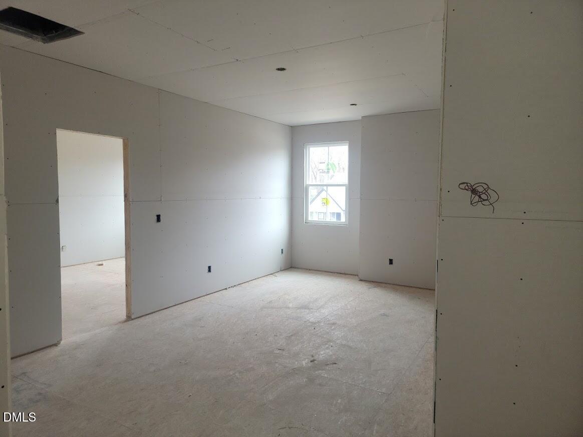 Unfinished spacious bedroom with drywall walls, large window, open doorway in Davidson Homes The Ashport G, Angier, NC