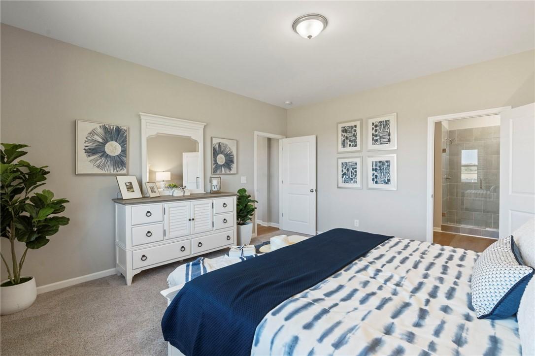 Serene master bedroom with navy duvet bed, white mirrored dresser, blue art, plants, and en-suite glass shower in Davidson Homes The Phoenix B, Opelika