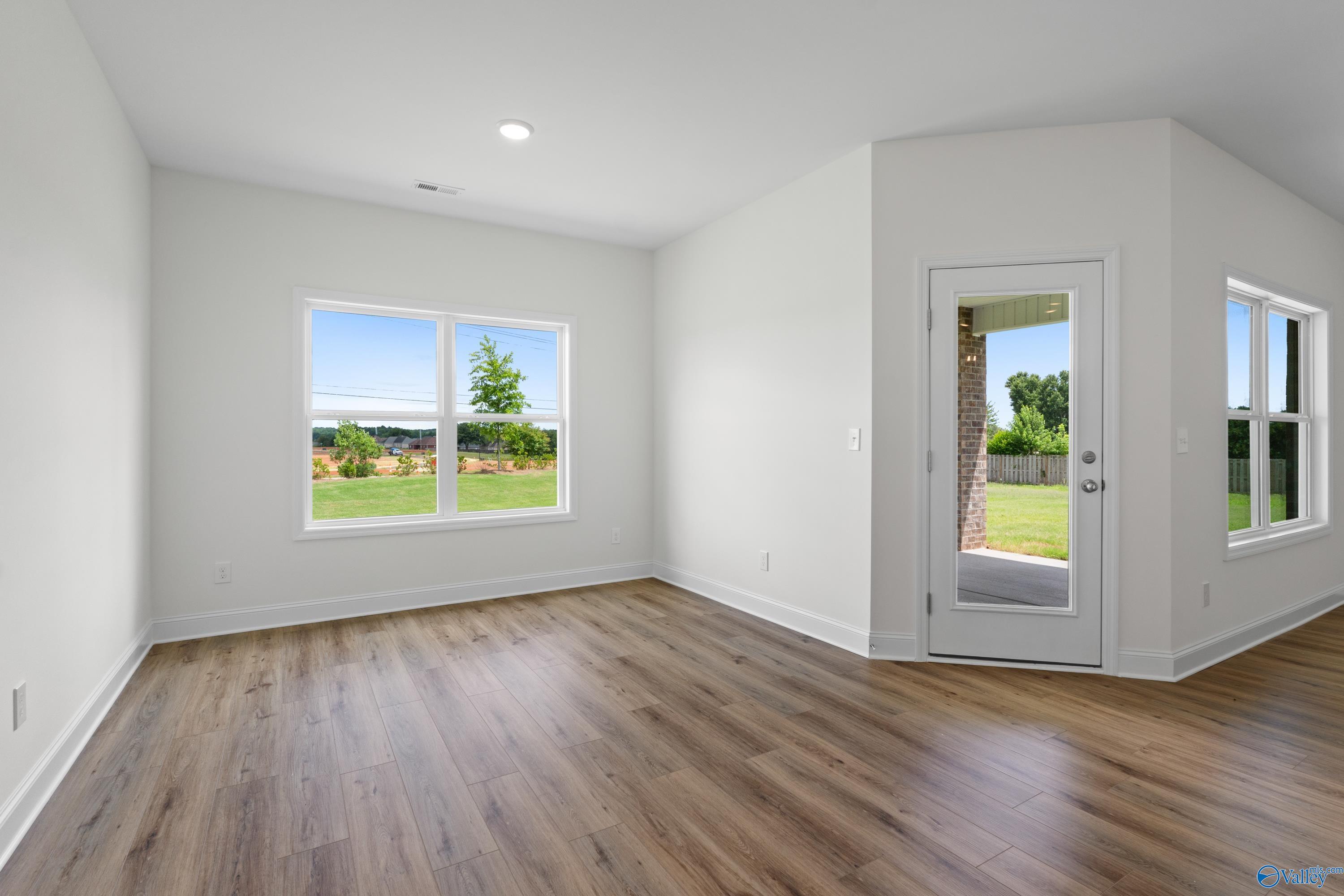 Bright bedroom with wood-look flooring and backyard access in The Everett B plan at The Meadows, Athens, Alabama.