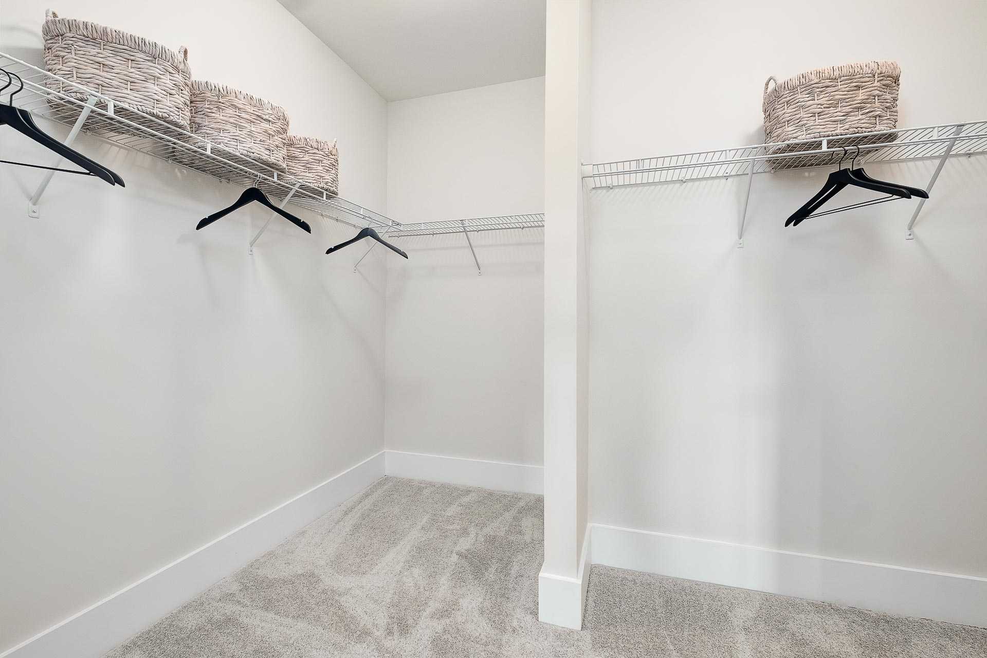 Spacious master walk-in closet in The Everett C featuring wire shelving, hangers, and wicker baskets on gray carpet