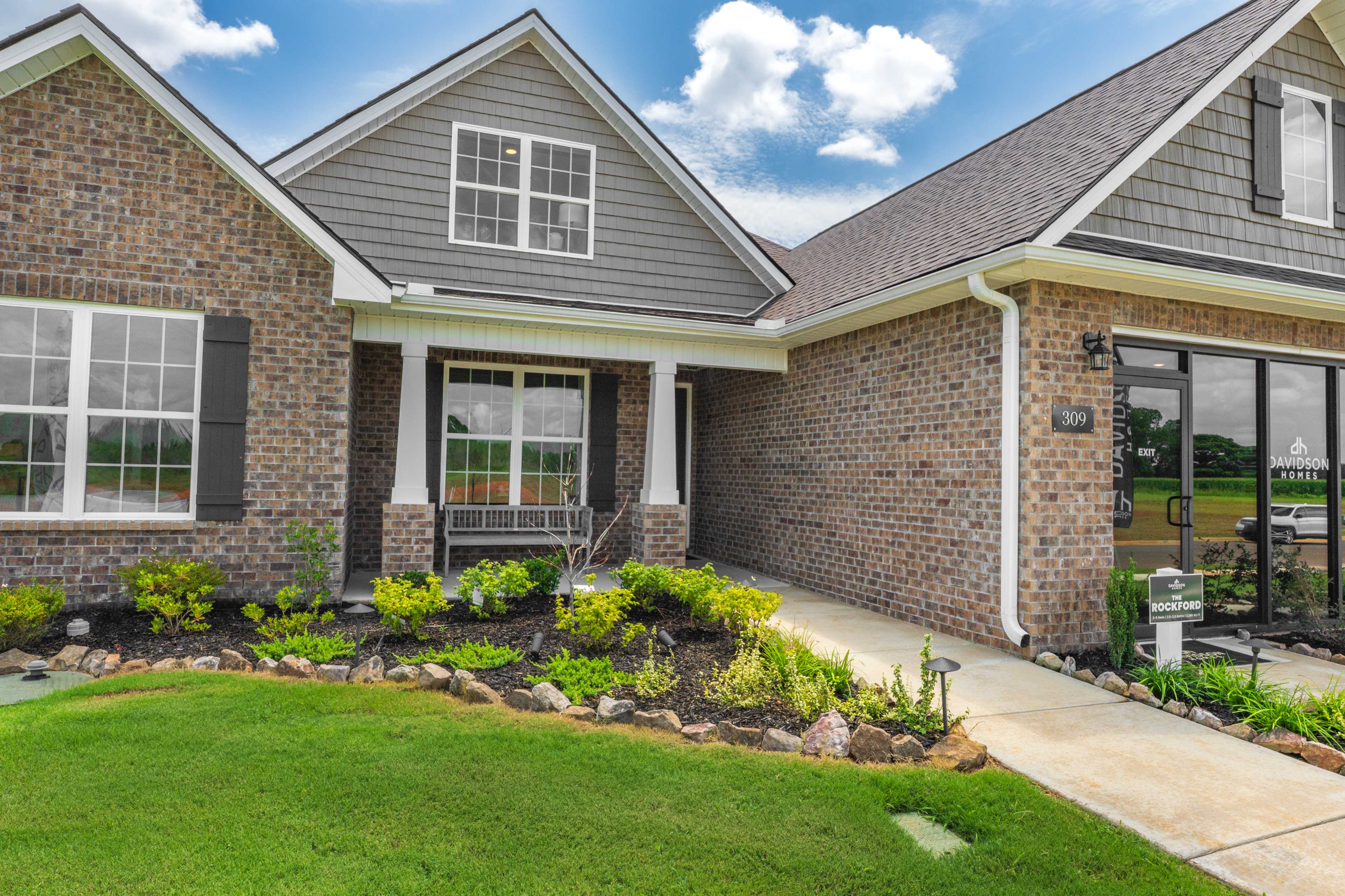 Brick home exteriors at Kendall Farms in Toney Alabama with gray siding, covered porches, porch swing and landscaped yard