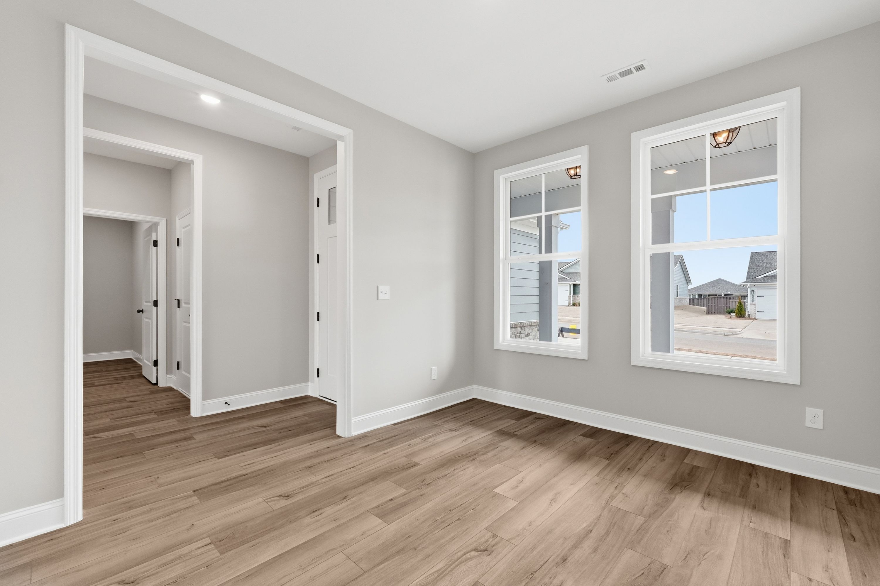 Spacious master bedroom in The Rockford with hardwood floors, gray walls, large windows overlooking neighborhood