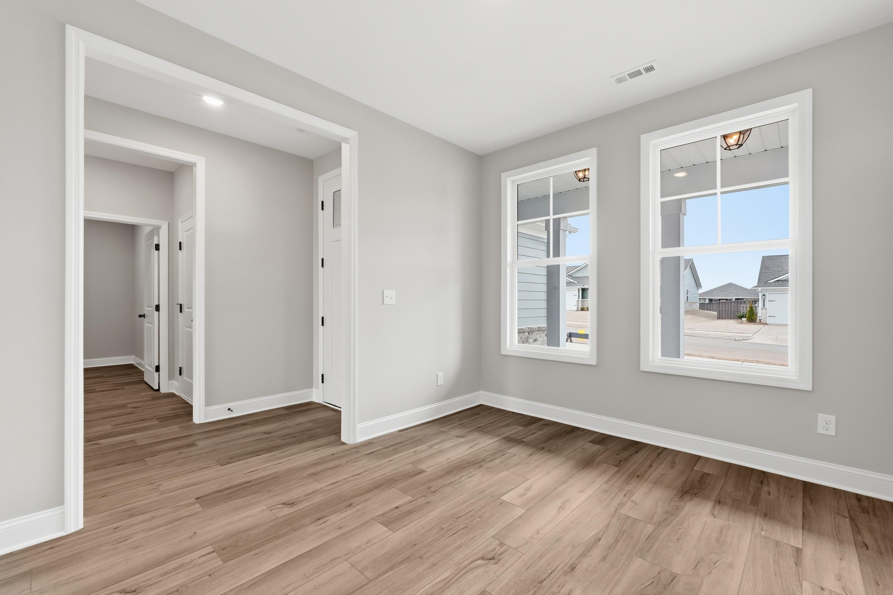 Spacious master bedroom in The Rockford with hardwood floors, gray walls, large windows overlooking neighborhood