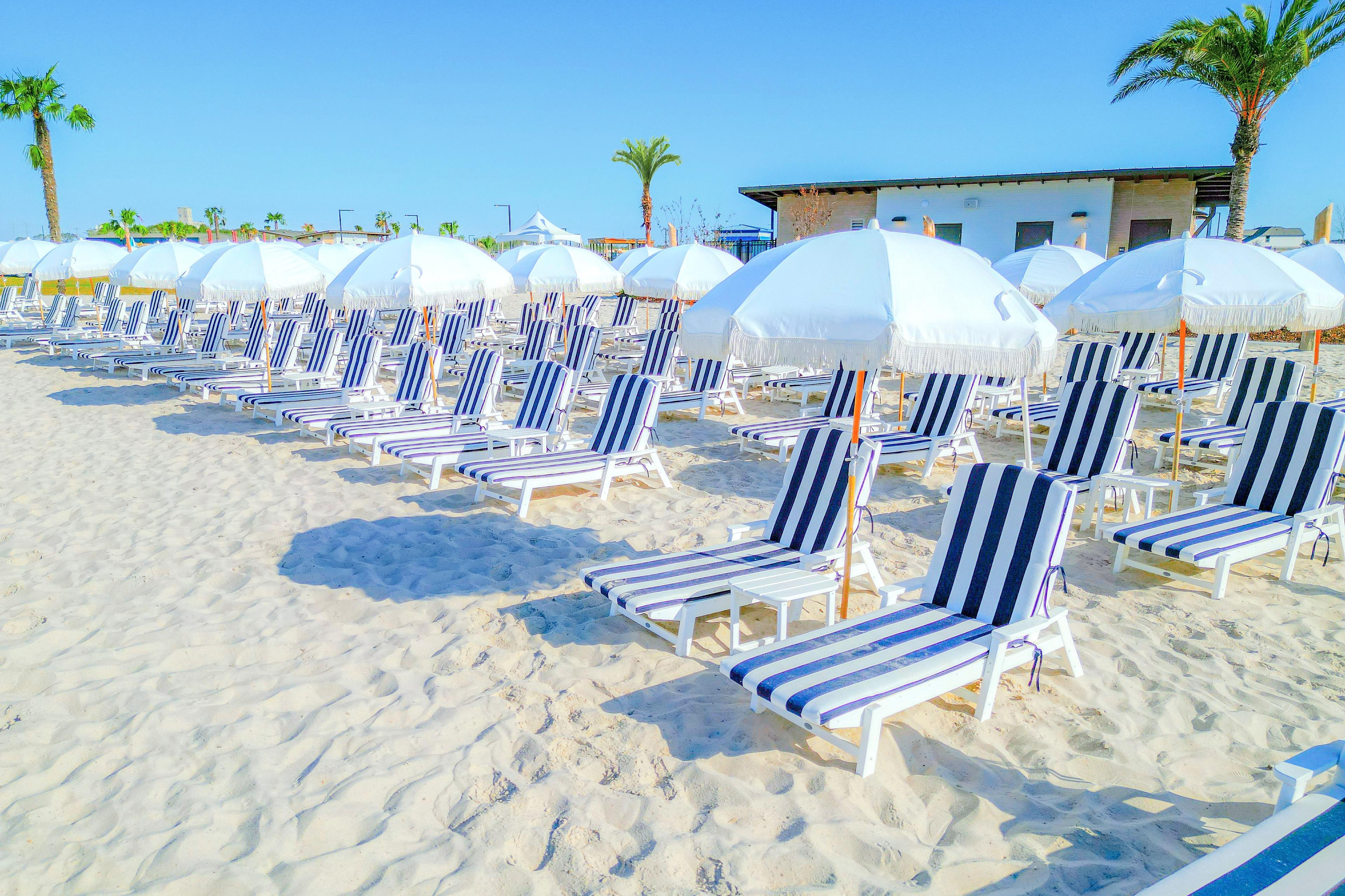 Resort-style beach club at River Ranch Meadows in Dayton Texas with striped lounge chairs umbrellas and palm trees