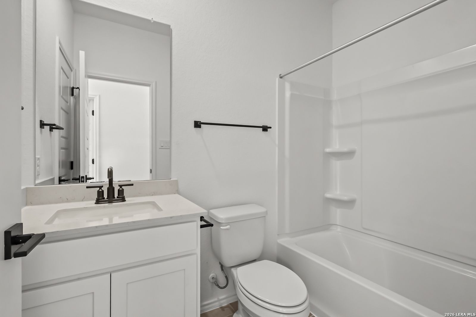 Modern full bathroom with white vanity, tub-shower combo, and matte black fixtures in The Florence B home, San Antonio.