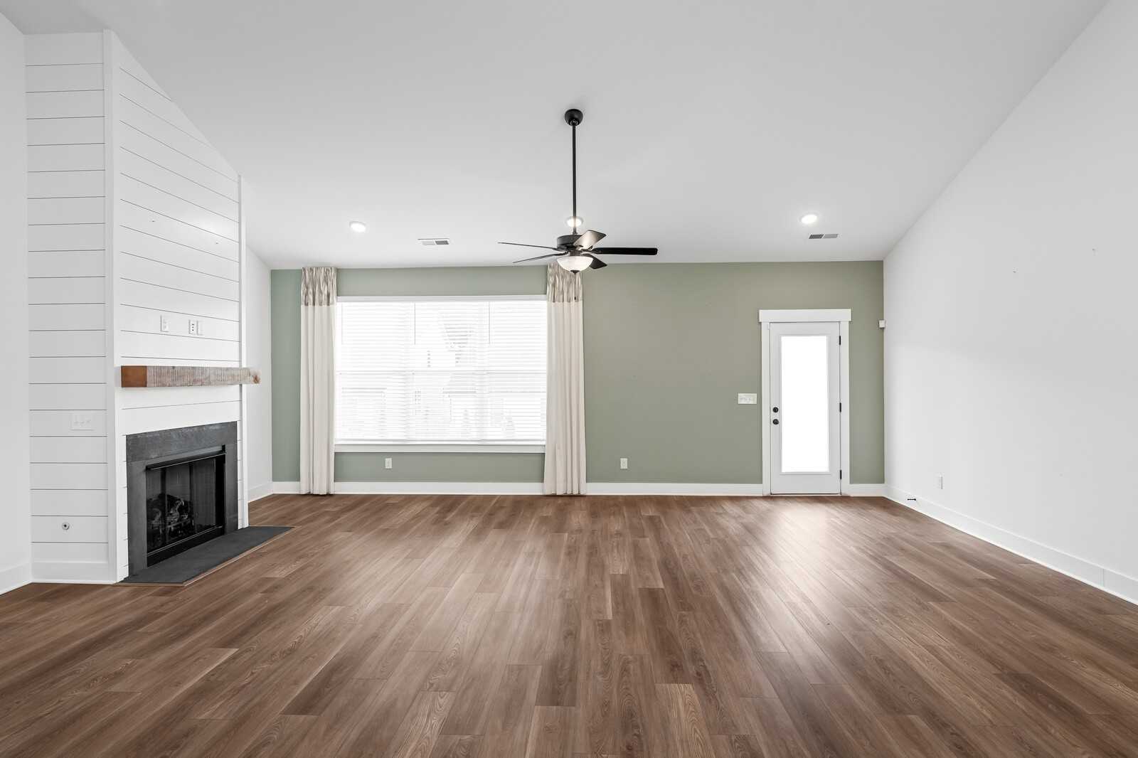 Cozy living room with shiplap fireplace, hardwood floors, and large windows in Davidson Homes Ridgeport, Gallatin, TN