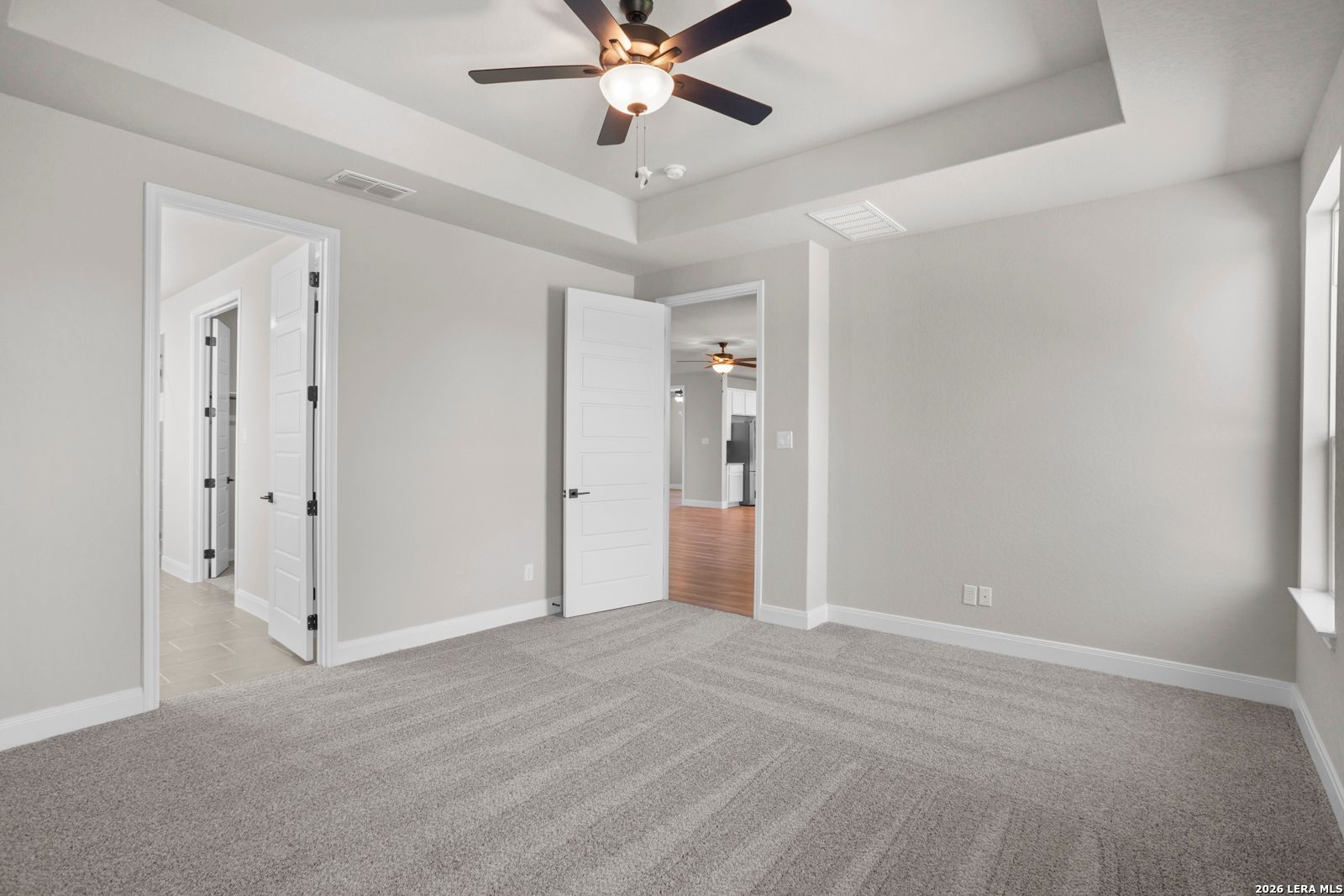 Spacious bedroom with tray ceiling and ceiling fan in The Jennings G floor plan by Davidson Homes in Ladera, San Antonio.