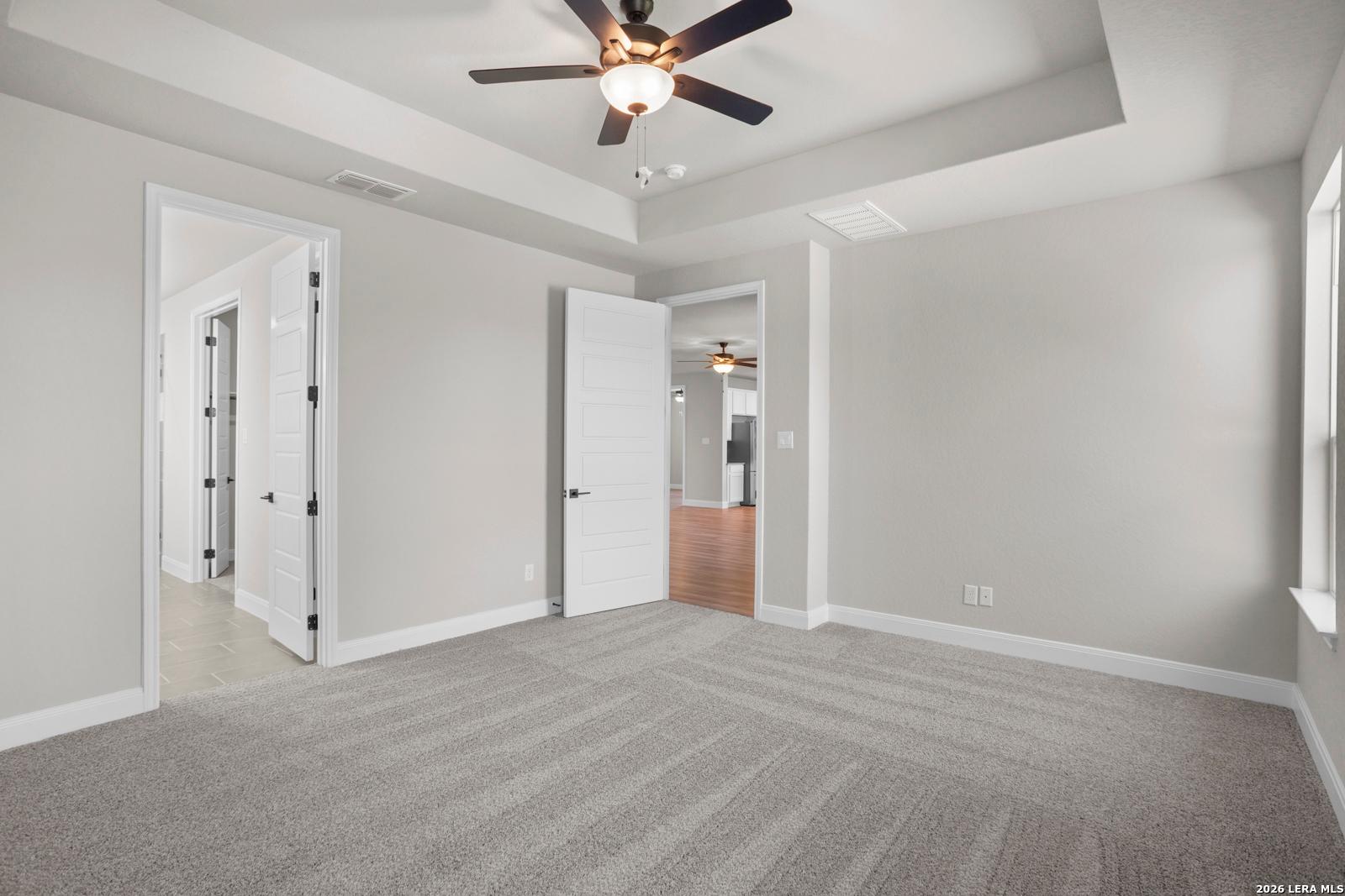 Spacious bedroom with tray ceiling and ceiling fan in The Jennings G floor plan by Davidson Homes in Ladera, San Antonio.