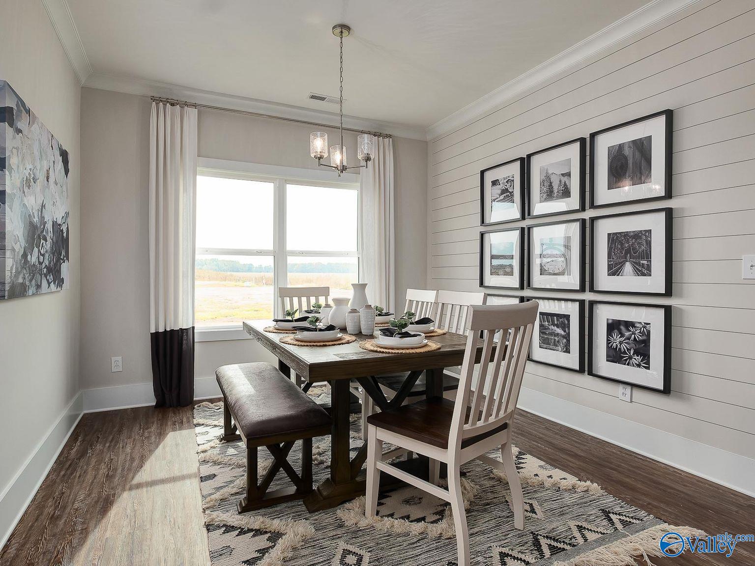 Elegant dining room with wooden table, benches, chairs, and shiplap walls in The Everett 4-bedroom home, Wood Trail, Toney, Alabama