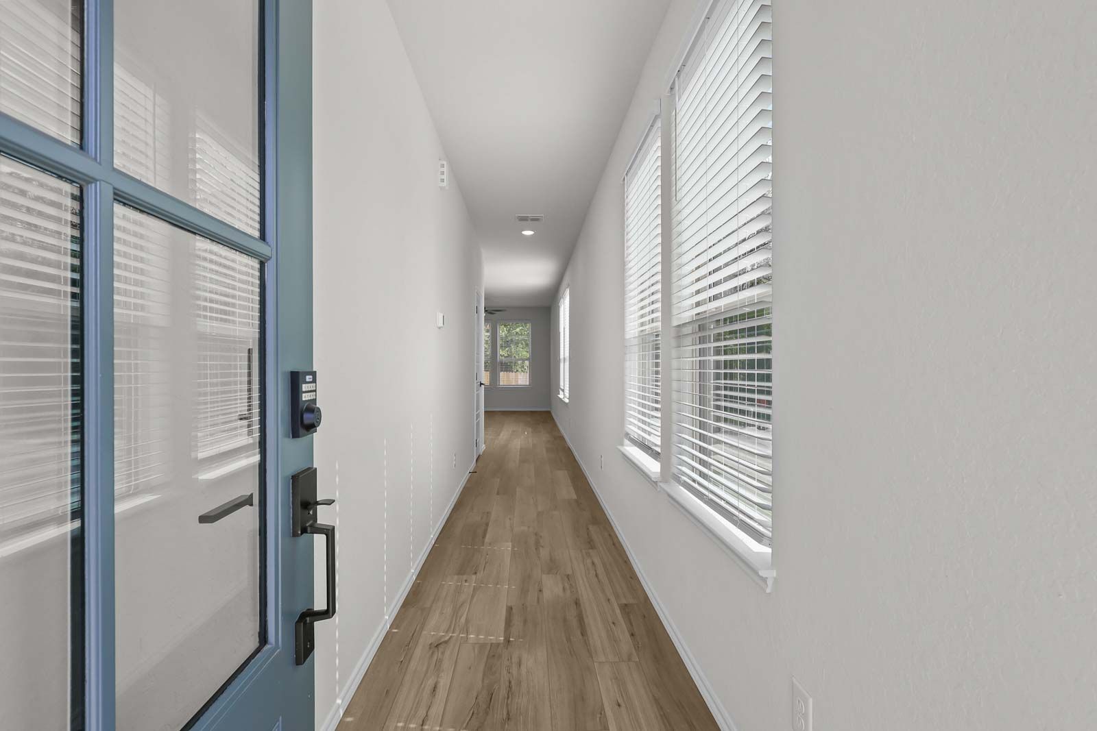 Bright entryway and long hallway of The Florence B featuring light wood flooring and natural light from tall windows.