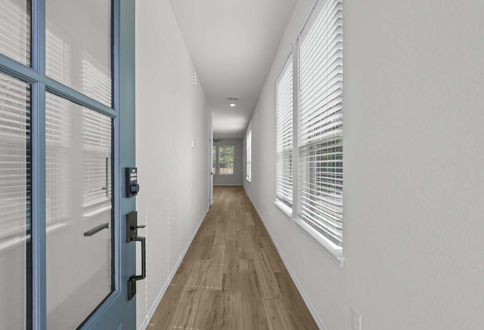 Bright entryway and long hallway of The Florence B featuring light wood flooring and natural light from tall windows.