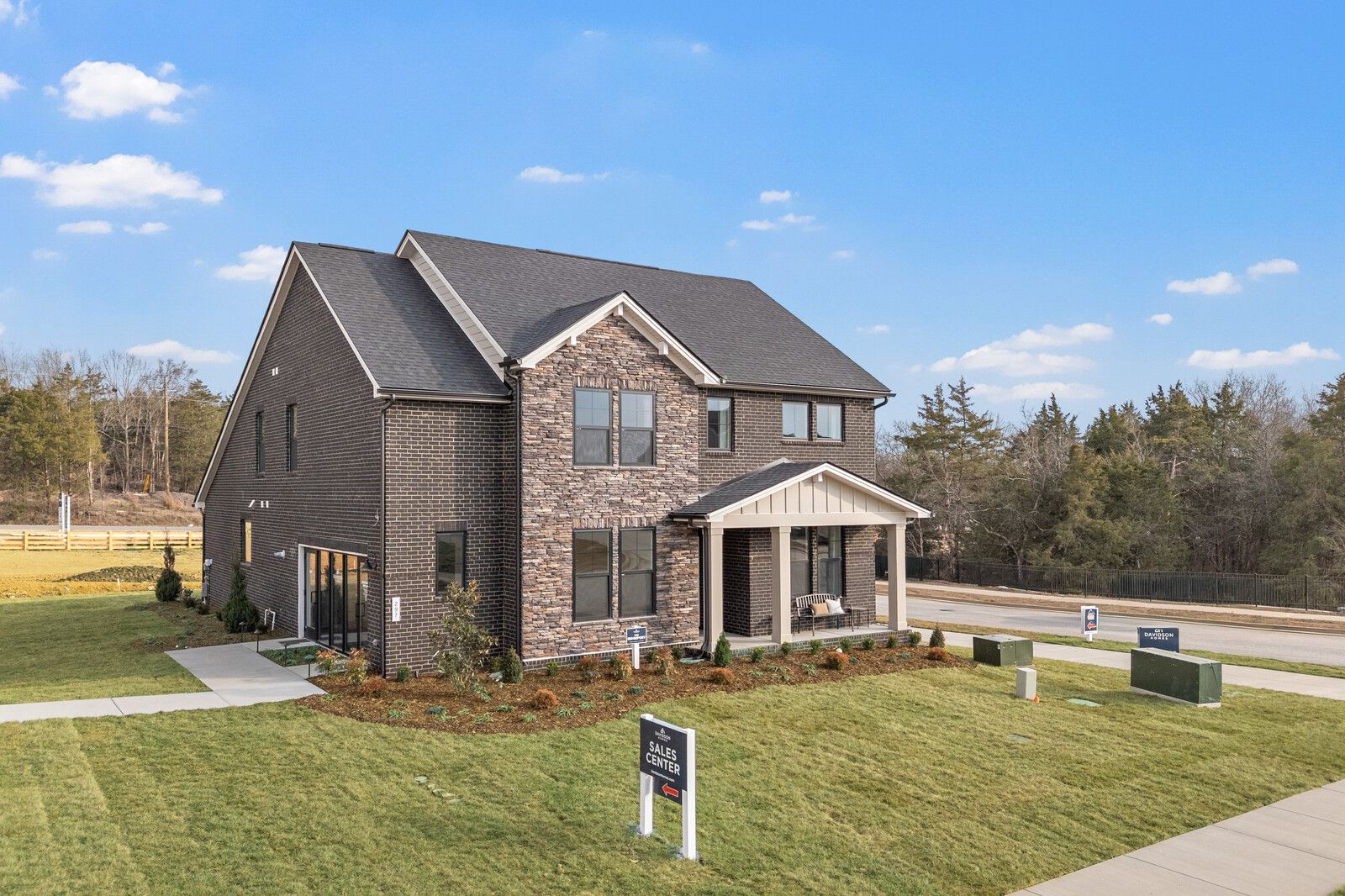 Two-story brick home exterior at Benders Cove in Mt. Juliet TN with covered porch, stone accents, and lush landscaping