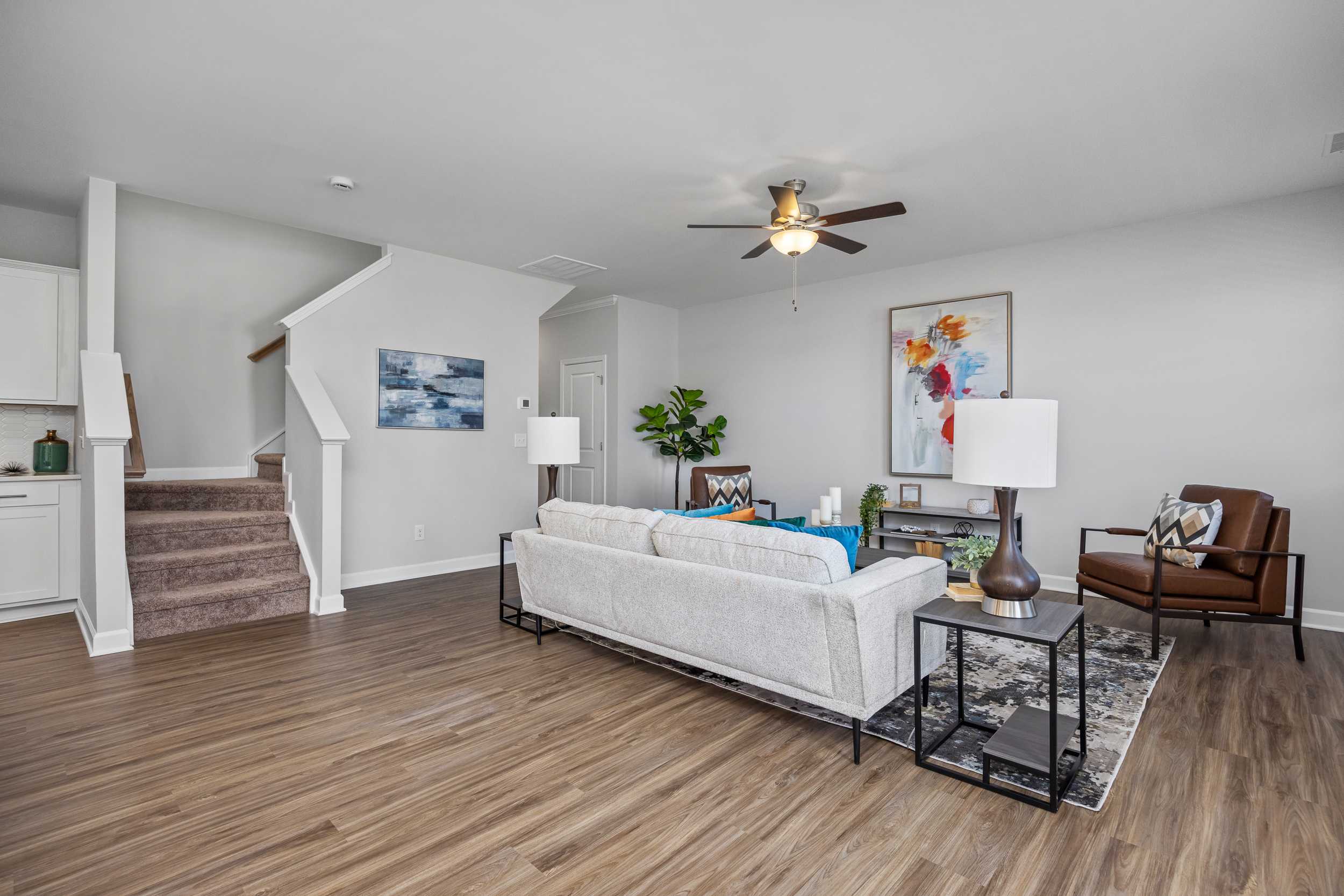 Spacious open-concept living room at Gregory Village Townhomes in Lillington NC with white sectional sofa, hardwood floors, and modern decor