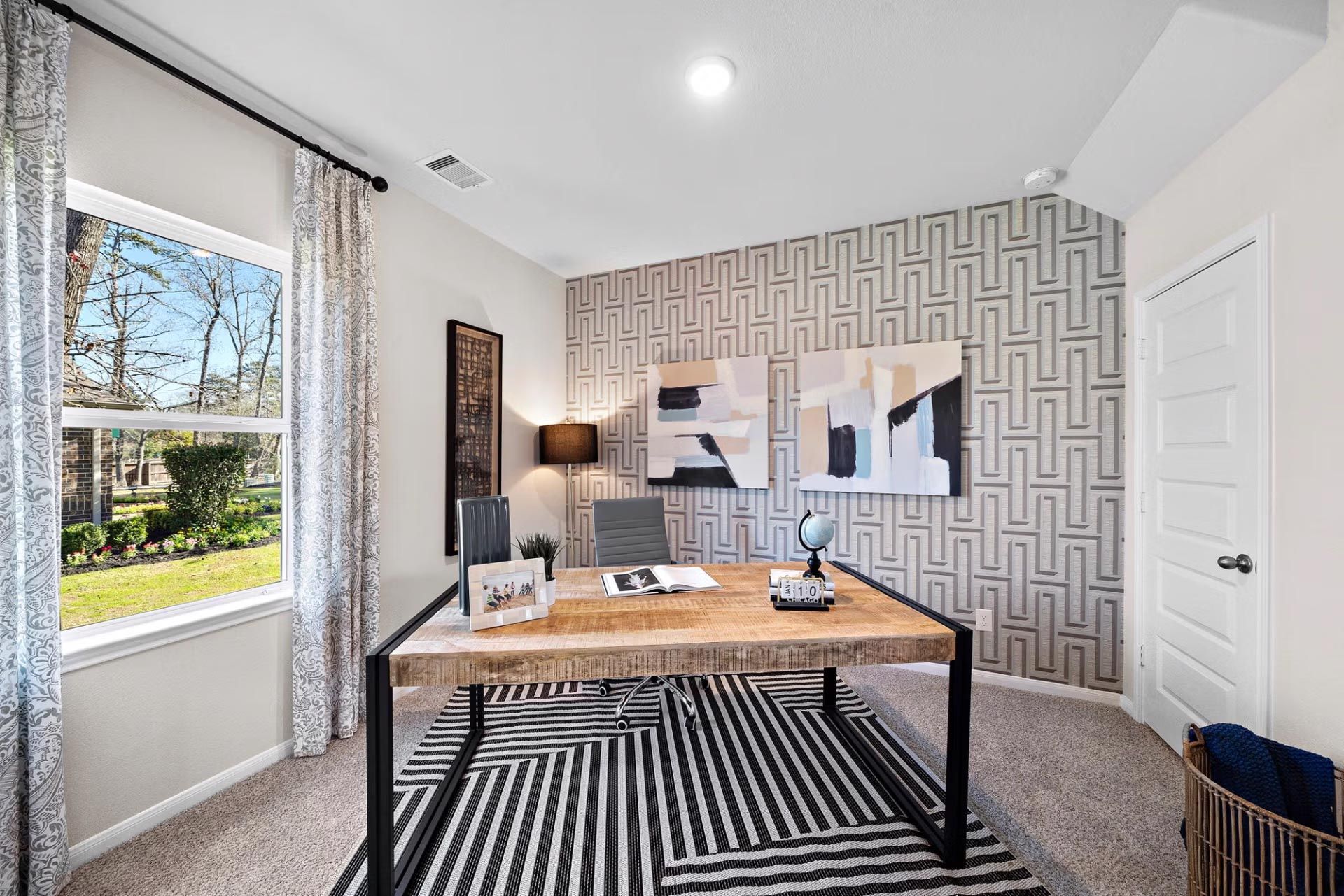 Modern home office at Saddle Creek Ranch in Cibolo TX with geometric wallpaper, wooden desk, abstract art, and large window