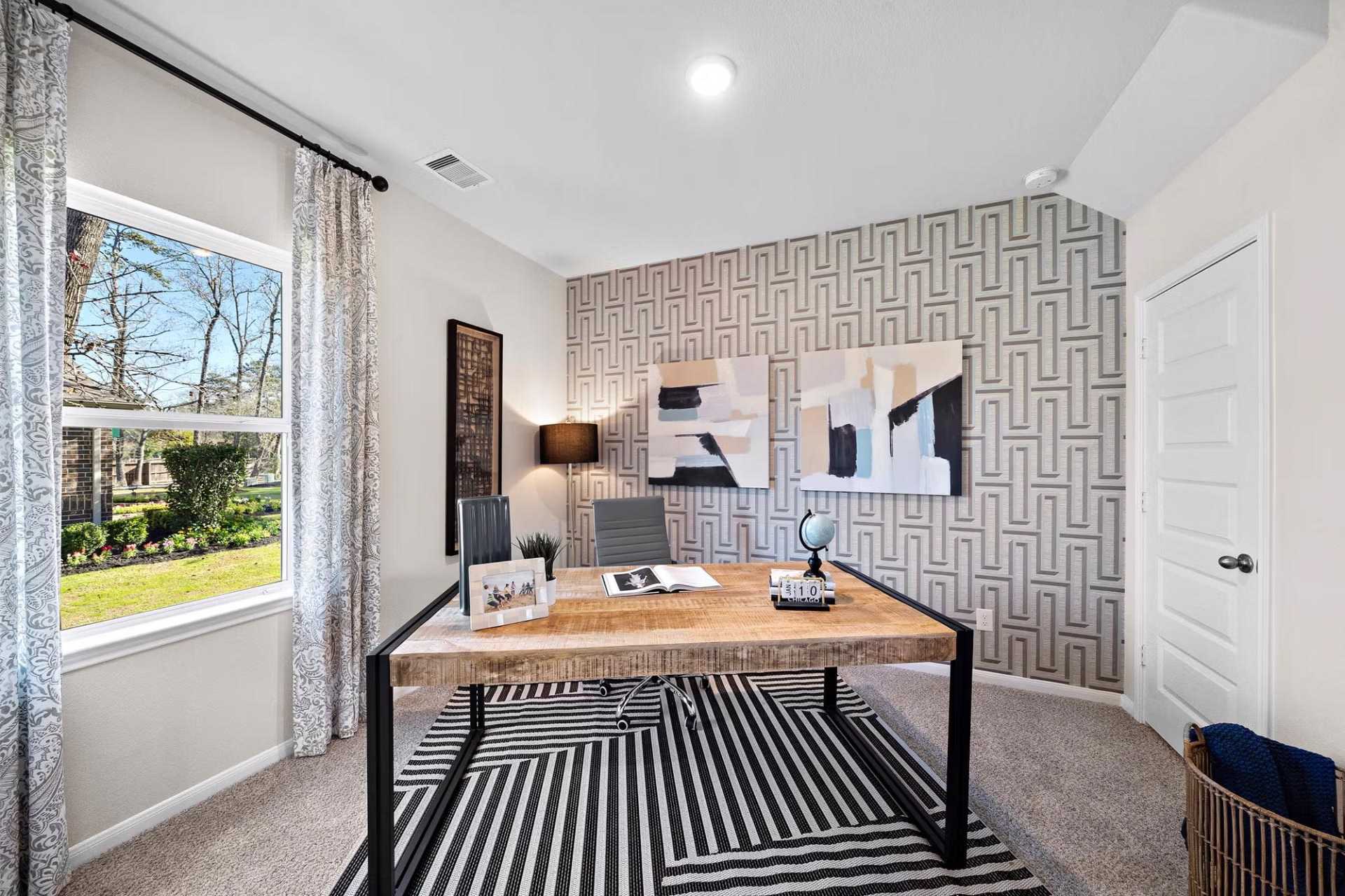 Modern home office at Saddle Creek Ranch in Cibolo TX with geometric wallpaper, wooden desk, abstract art, and large window