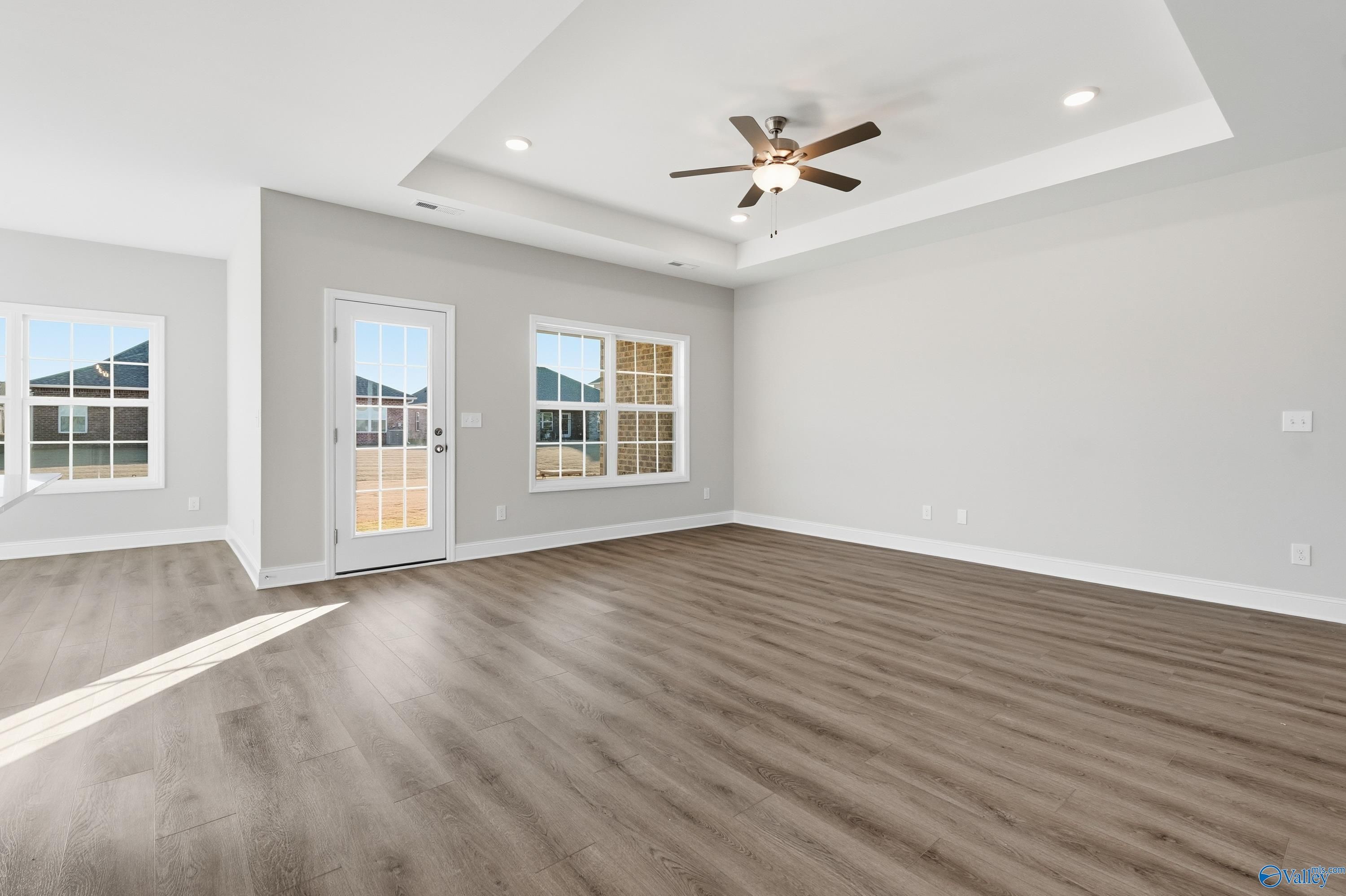 Spacious living room with ceiling fan, large windows, sliding door, and hardwood floors in The Montgomery B, Toney, Alabama