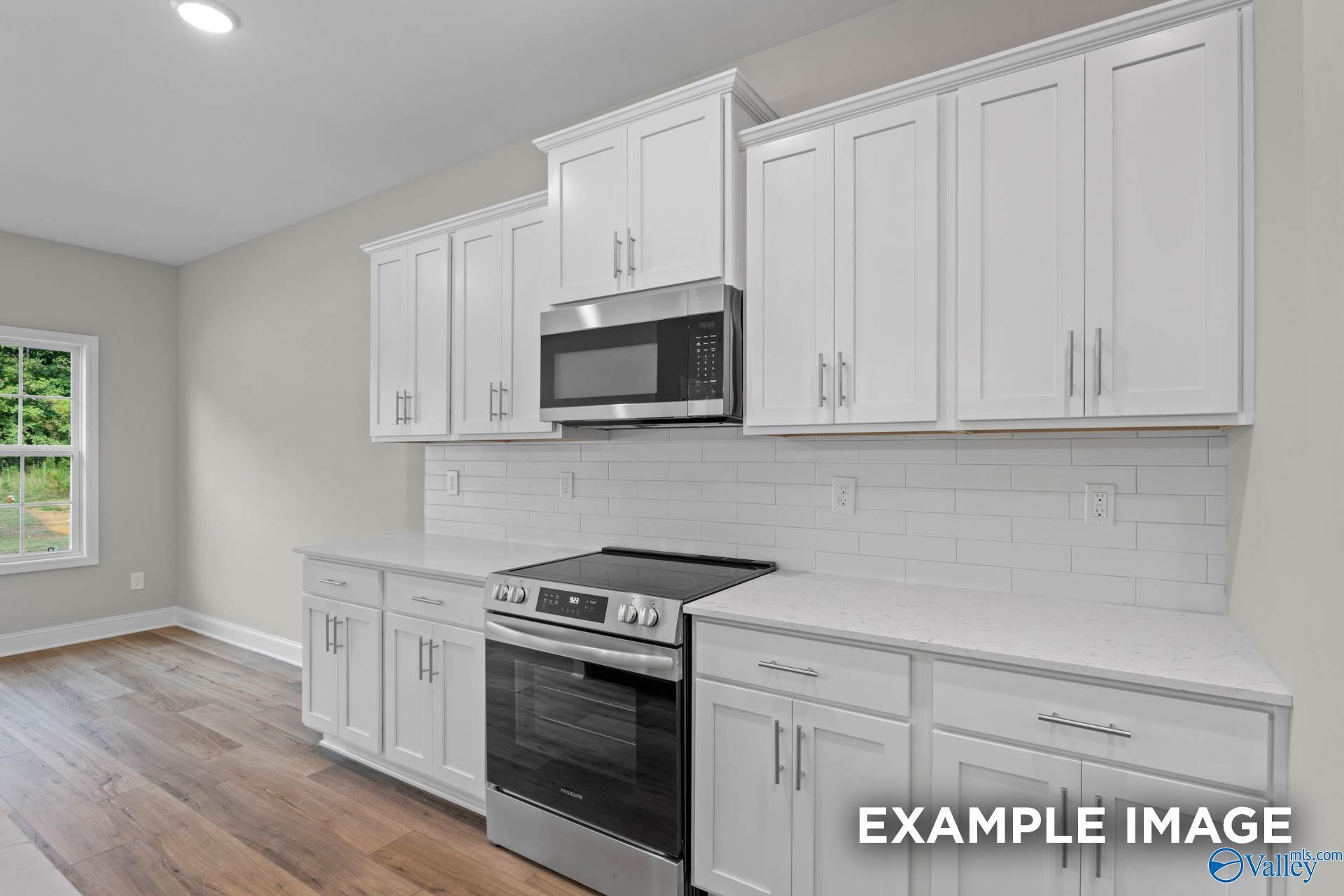 Modern kitchen with white shaker cabinets, subway tile backsplash, and stainless appliances in The Montgomery B home plan.