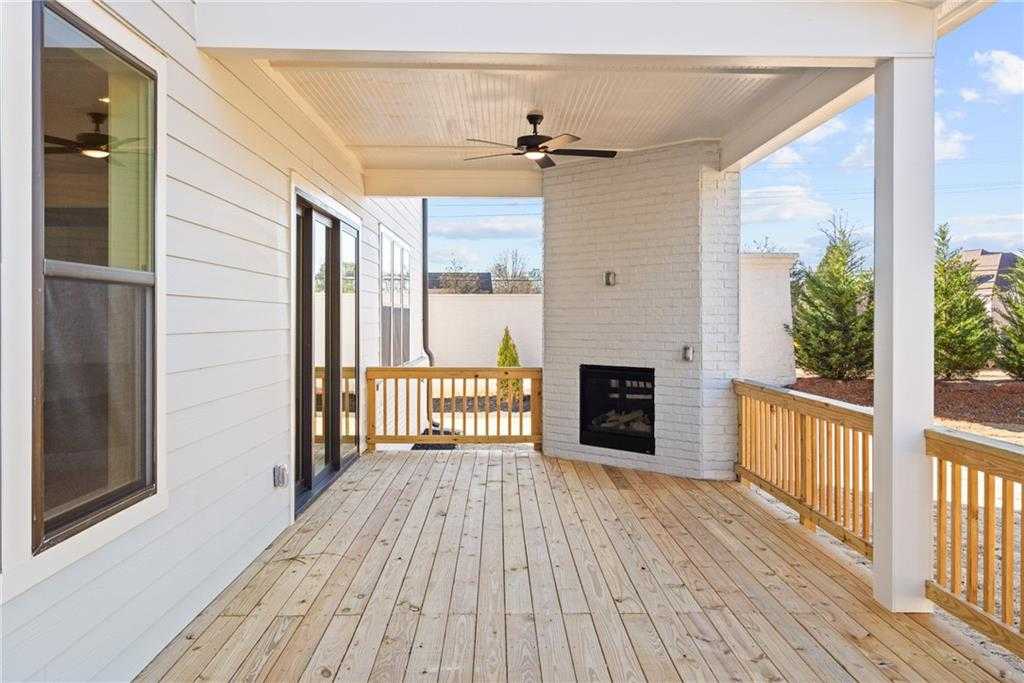 Covered wooden deck with ceiling fan and brick outdoor fireplace in Davidson Homes The Arlington A, East Cobb, Georgia