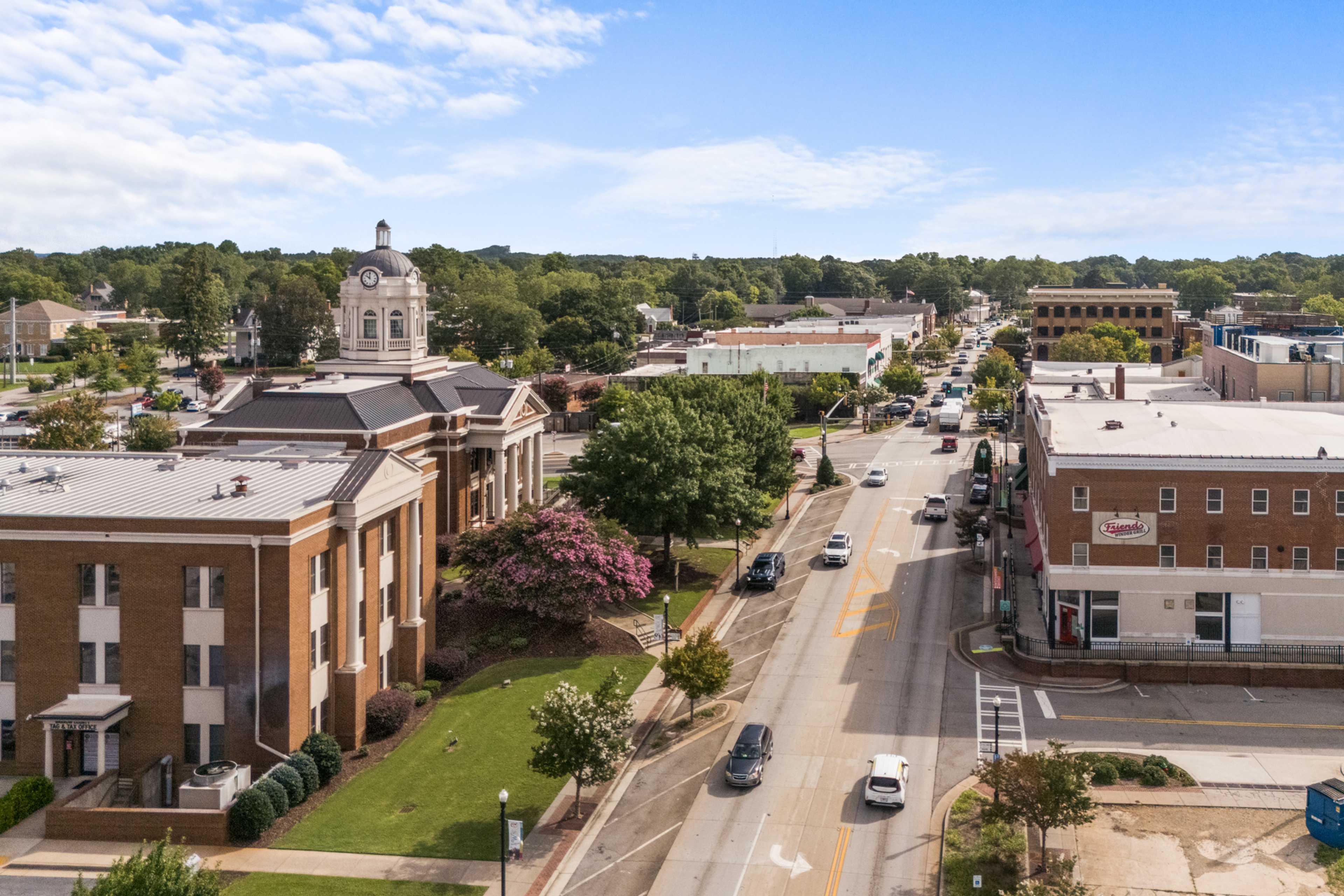 Aerial view of historic downtown Winder Georgia with courthouse steeple, brick buildings, tree-lined streets and traffic