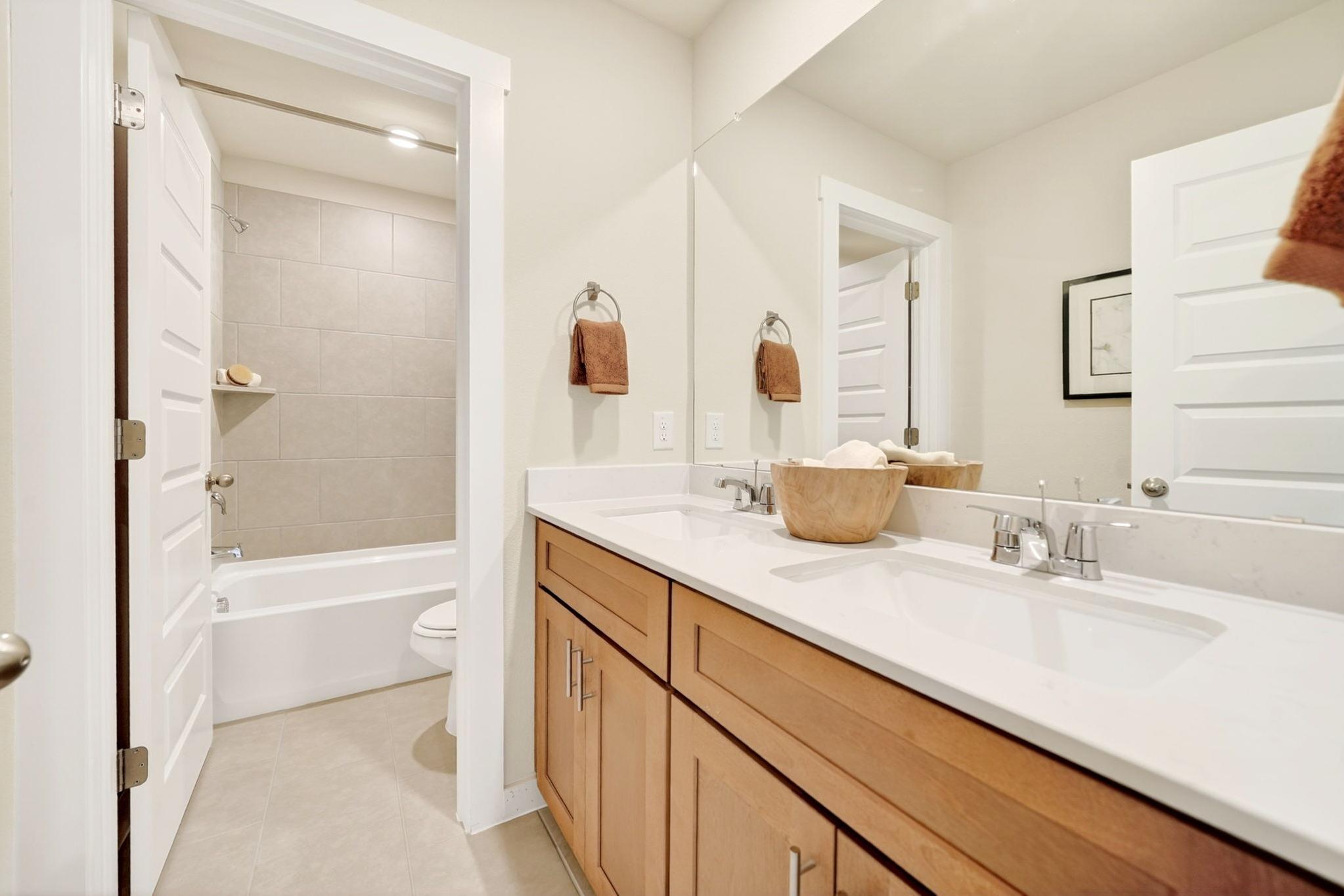 Contemporary bathroom with walk-in shower, bathtub, double oak vanity, quartz counters in Heartland, Texas