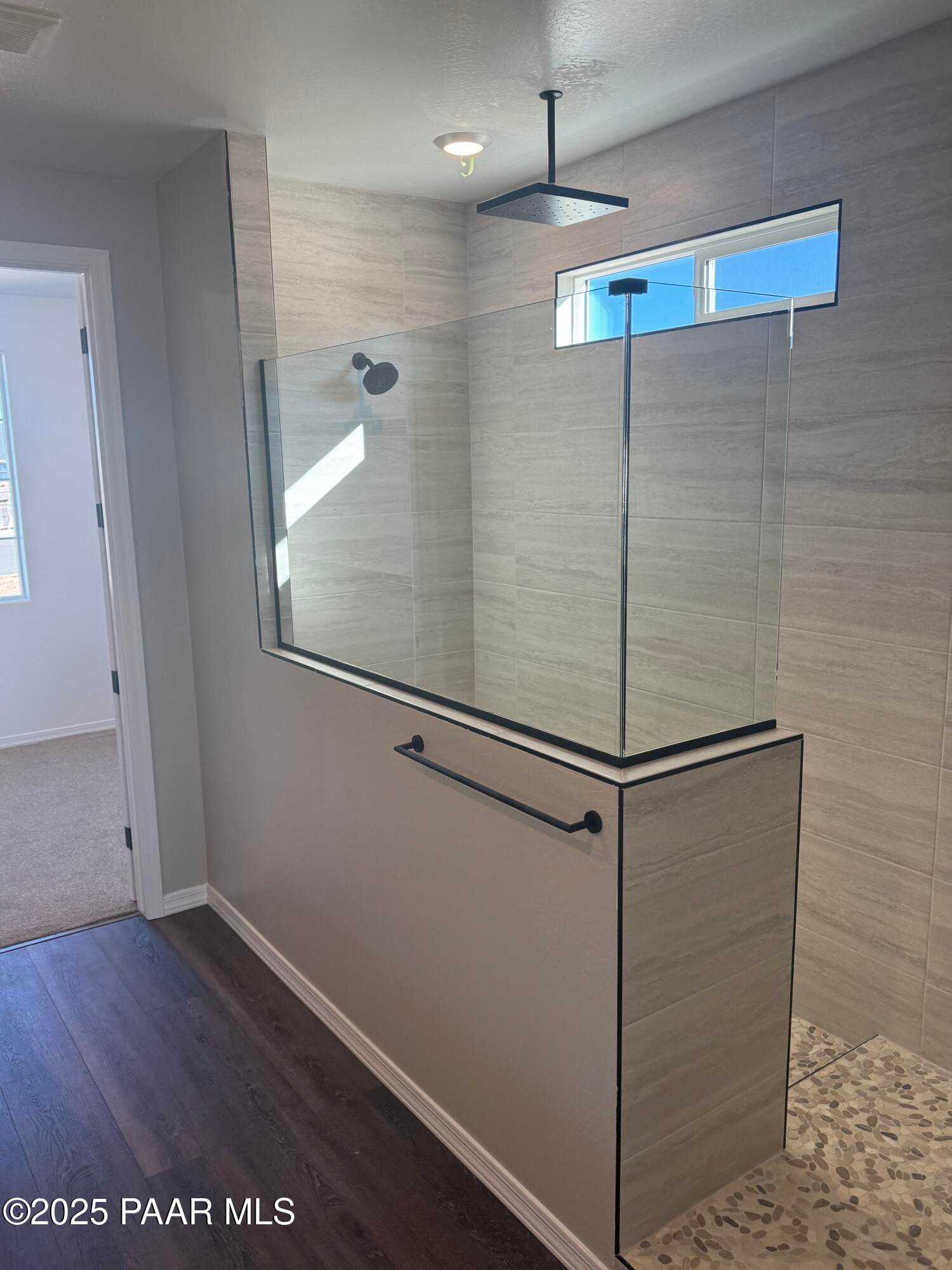 Modern frameless glass shower with rain head, tiled walls, and pebble floor in master bath, Davidson Homes The Monarch E, Prescott AZ