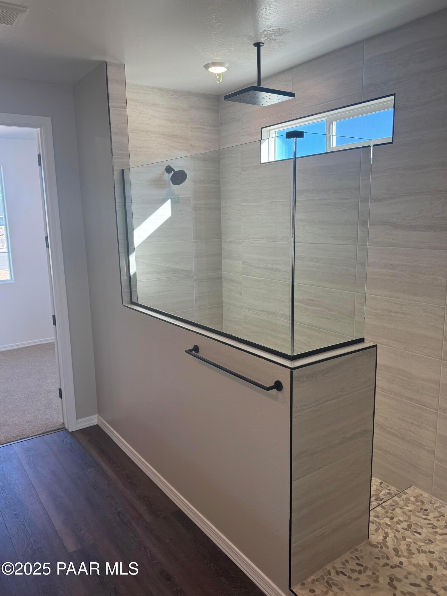 Modern frameless glass shower with rain head, tiled walls, and pebble floor in master bath, Davidson Homes The Monarch E, Prescott AZ