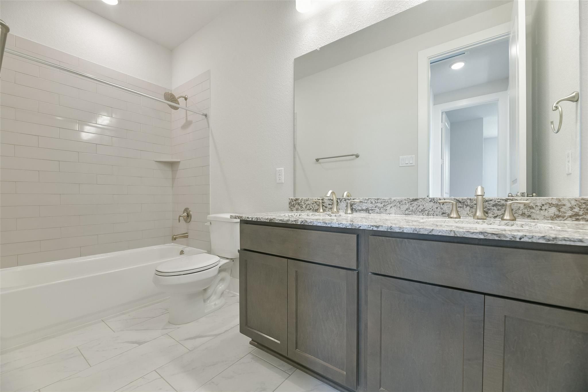 Spacious master bath with double vanity, gray shaker cabinets, quartz counters, soaking tub, and walk-in shower in Davidson Homes The Edward A, Lago Mar