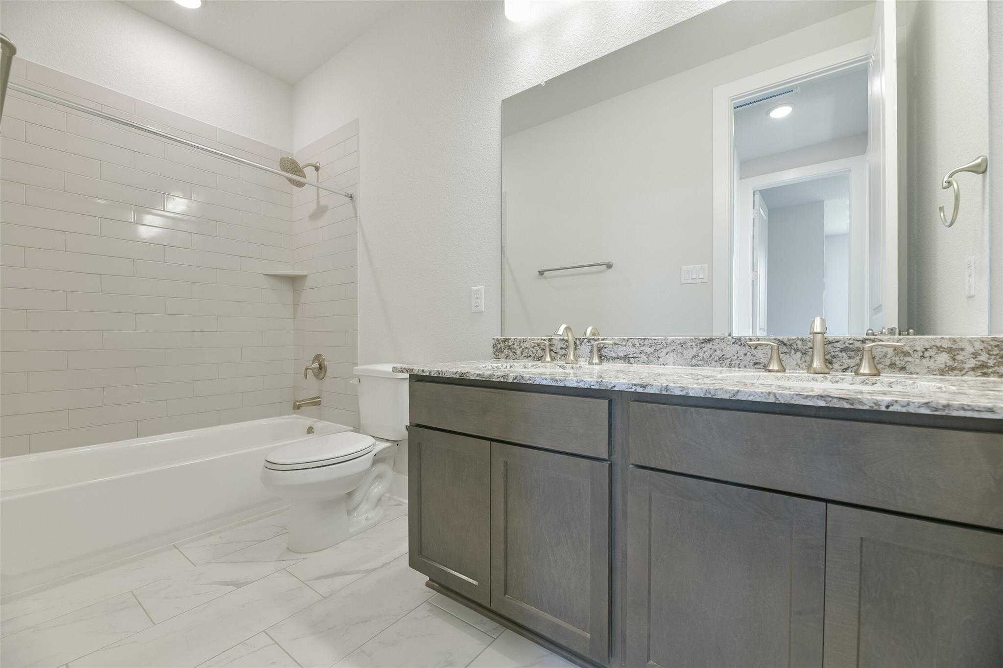 Spacious master bath with double vanity, gray shaker cabinets, quartz counters, soaking tub, and walk-in shower in Davidson Homes The Edward A, Lago Mar