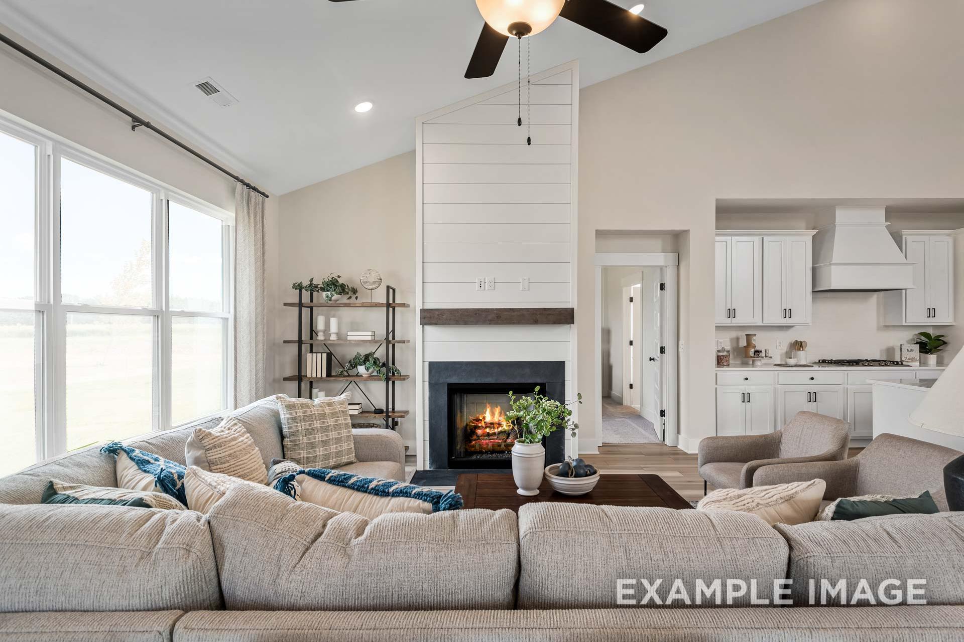 Cozy living room in The Ridgeport B with shiplap fireplace, beige sectional sofa, large windows, and kitchen view