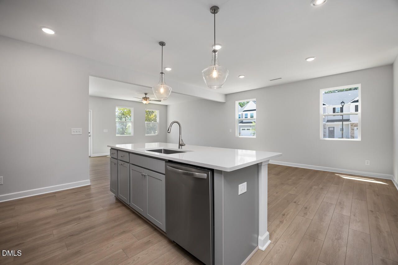 Modern island kitchen with grey cabinets and white countertops in The Adalynn B floor plan at Gregory Village, Lillington.