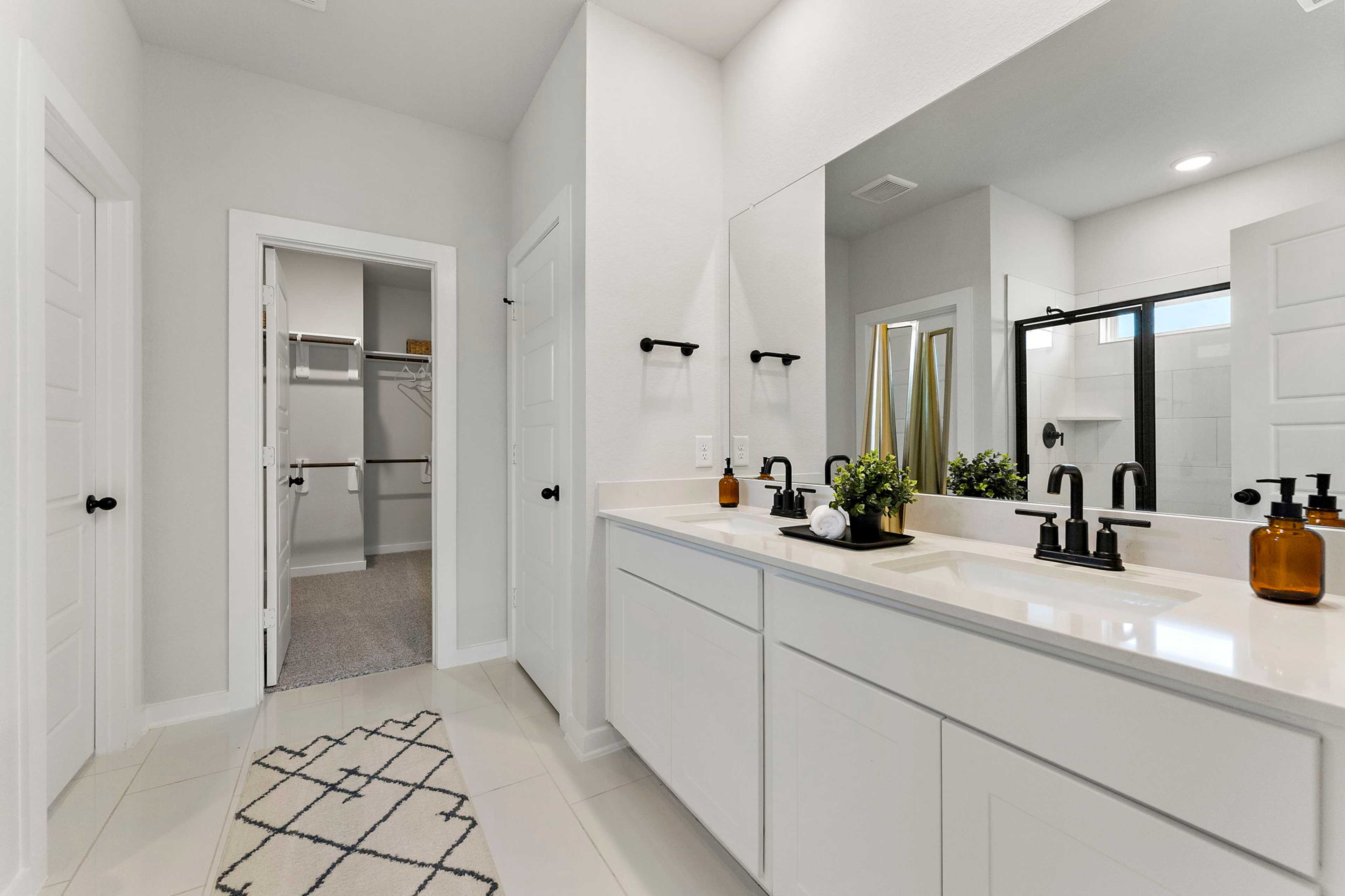 Spacious master bathroom at Sundance Cove in Crosby Texas with white double vanity black fixtures quartz counters and walk-in shower