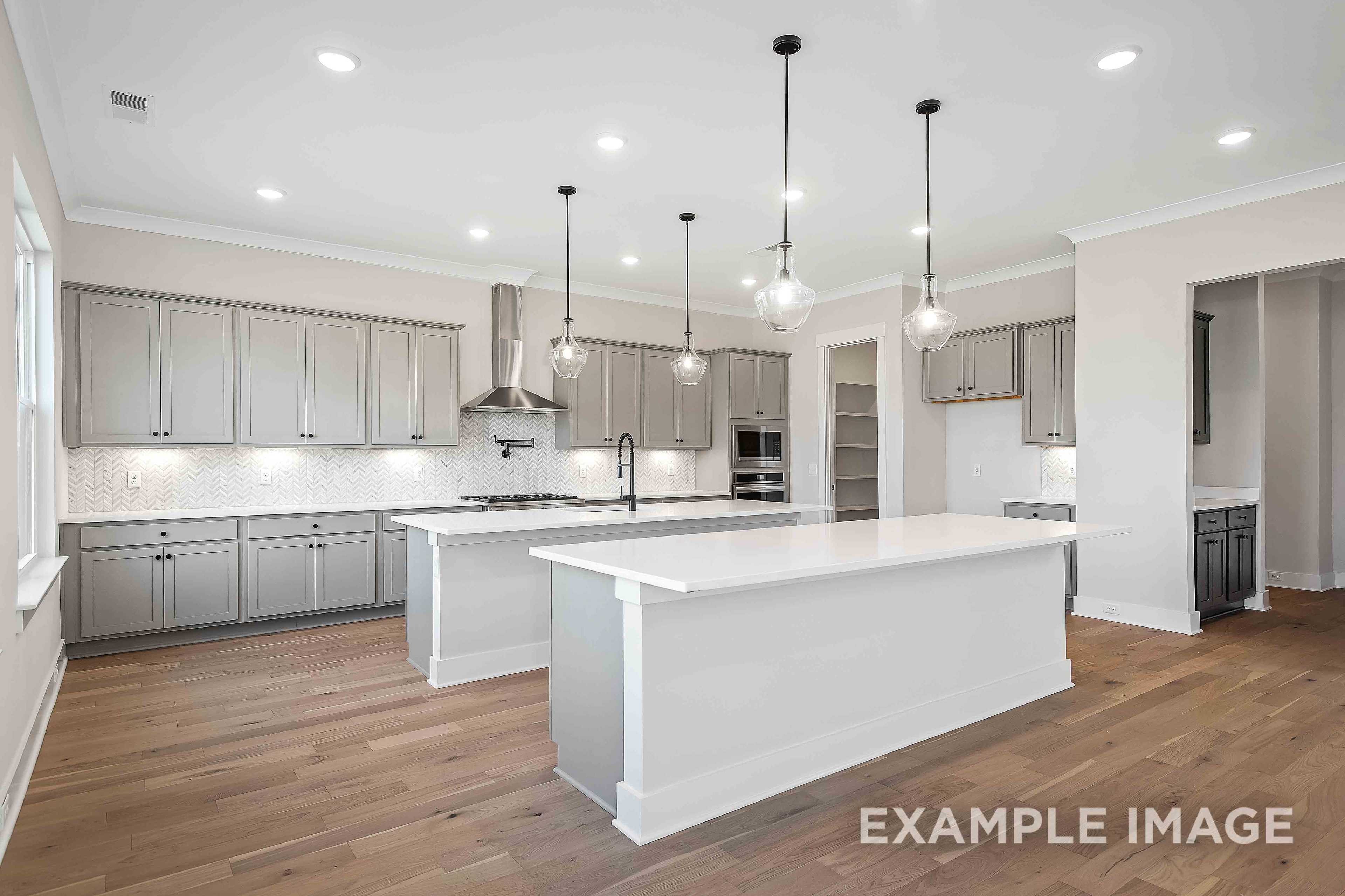 Gourmet kitchen in The Alston A with double white quartz islands, gray cabinets, stainless appliances, and hardwood floors