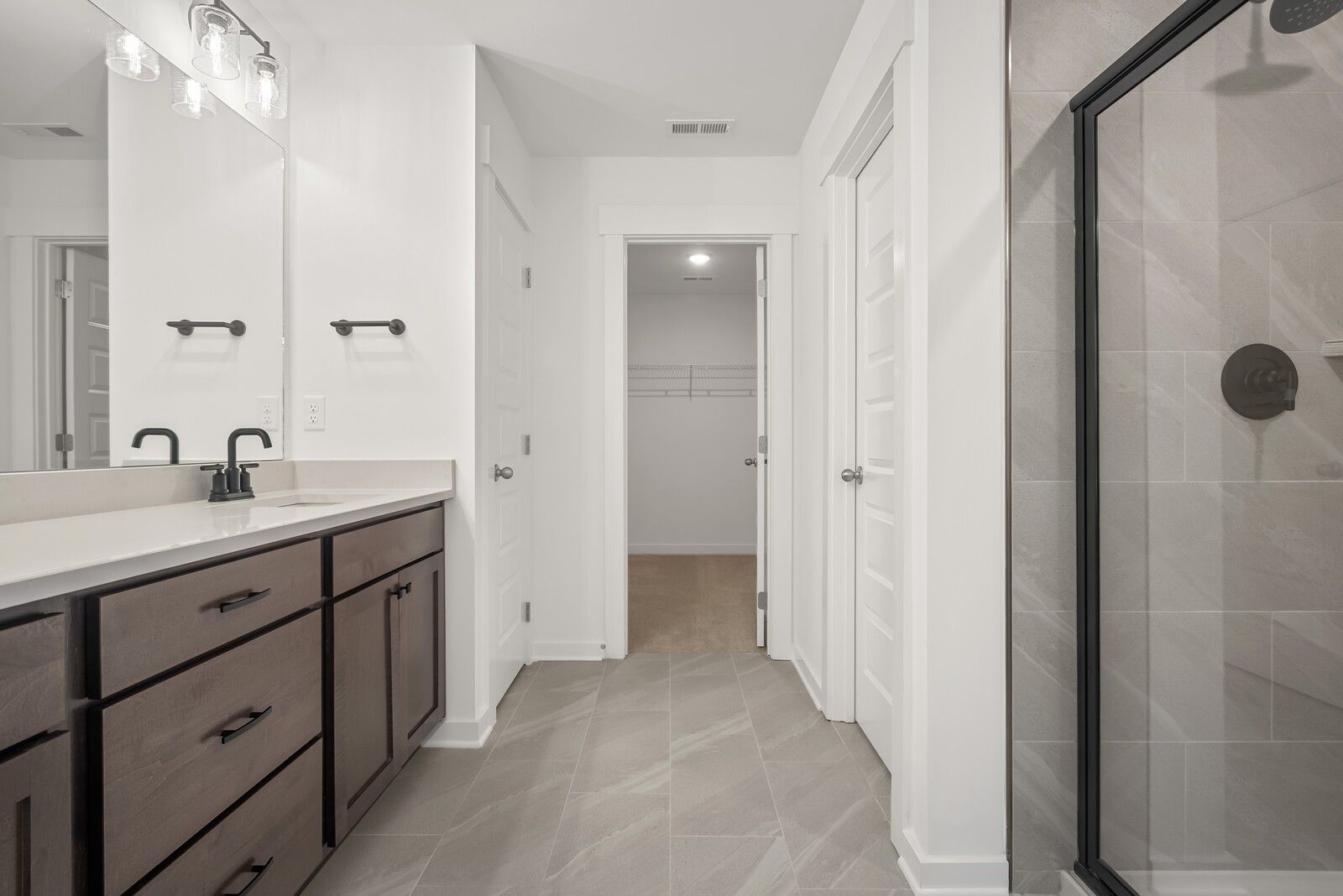 Modern master bathroom featuring double vanity, frameless glass shower, and walk-in closet in Davidson Homes The Logan C, Gallatin, TN