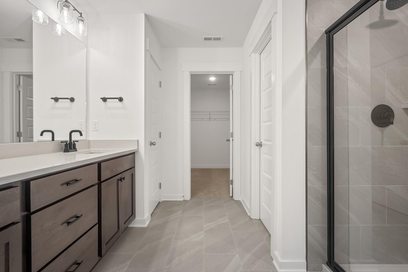 Modern master bathroom featuring double vanity, frameless glass shower, and walk-in closet in Davidson Homes The Logan C, Gallatin, TN