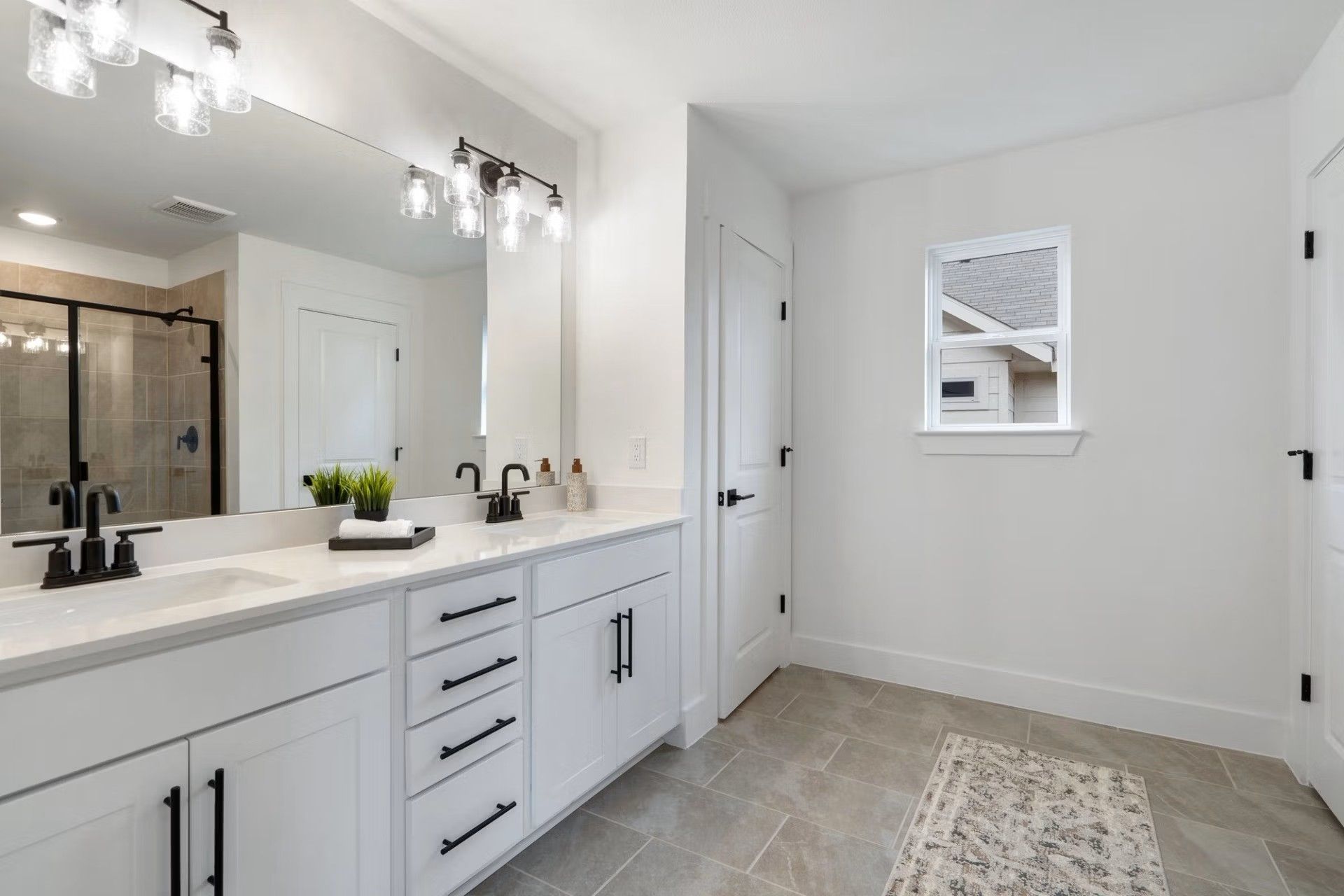 Elegant master bathroom with double vanity, frameless shower, and white shaker cabinets in Davidson Homes The Wake D, Wylie, Texas