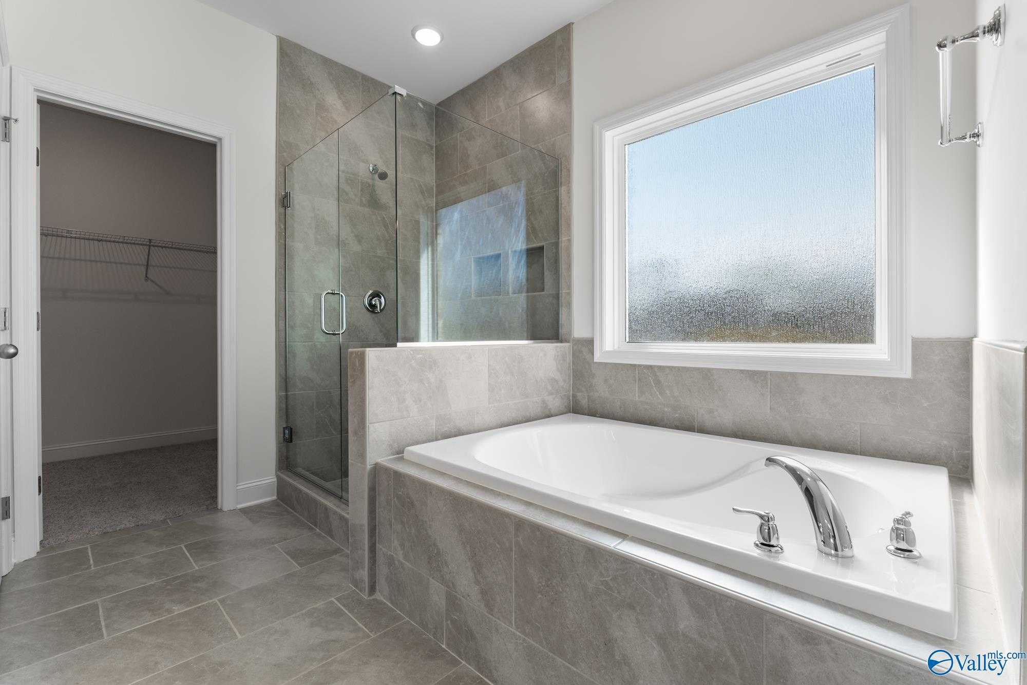 Luxurious master bathroom featuring glass shower, freestanding soaking tub, and frosted window in Davidson Homes The Harrison, Meridianville, Alabama