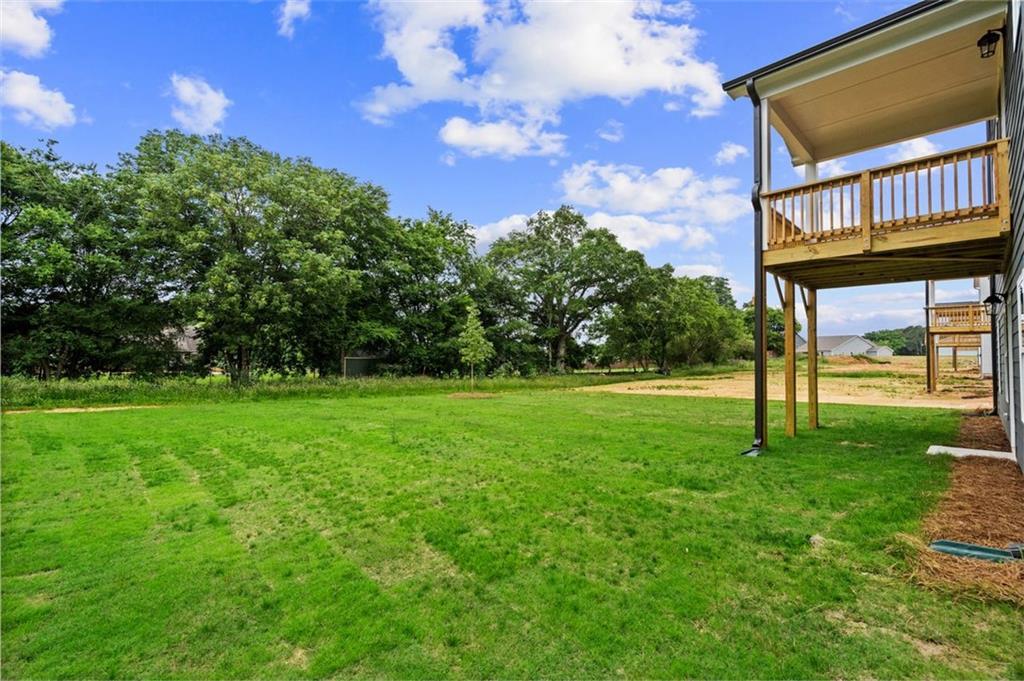 Elevated wooden deck with railing overlooking lush green lawn and trees in Davidson Homes The Hickory B at Wehunt Meadows, Hoschton, Georgia
