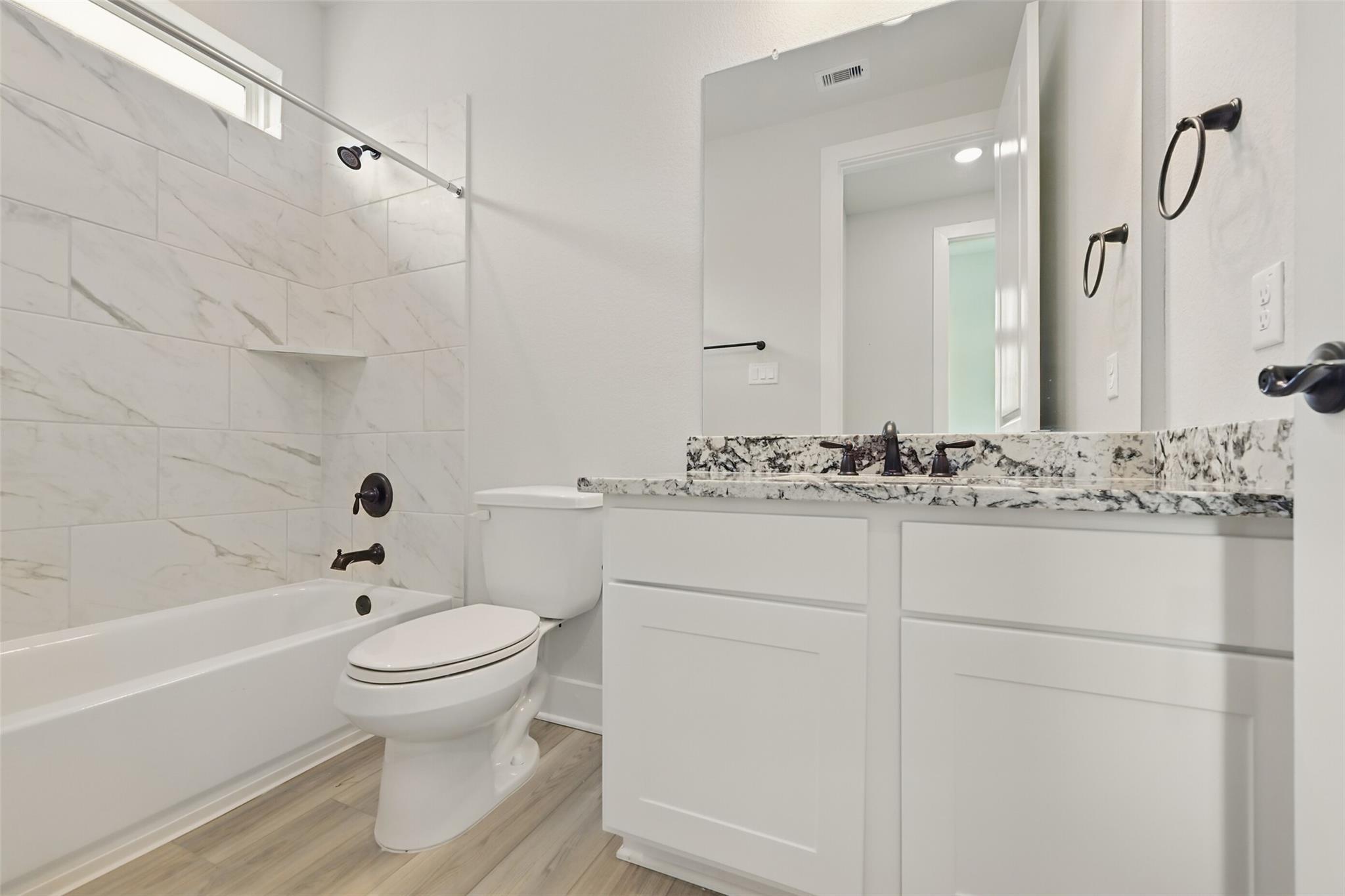 Elegant bathroom featuring white subway tile walls, freestanding tub, double quartz vanity, and large mirror in Davidson Homes The Victoria C, Lago Mar, Texas City