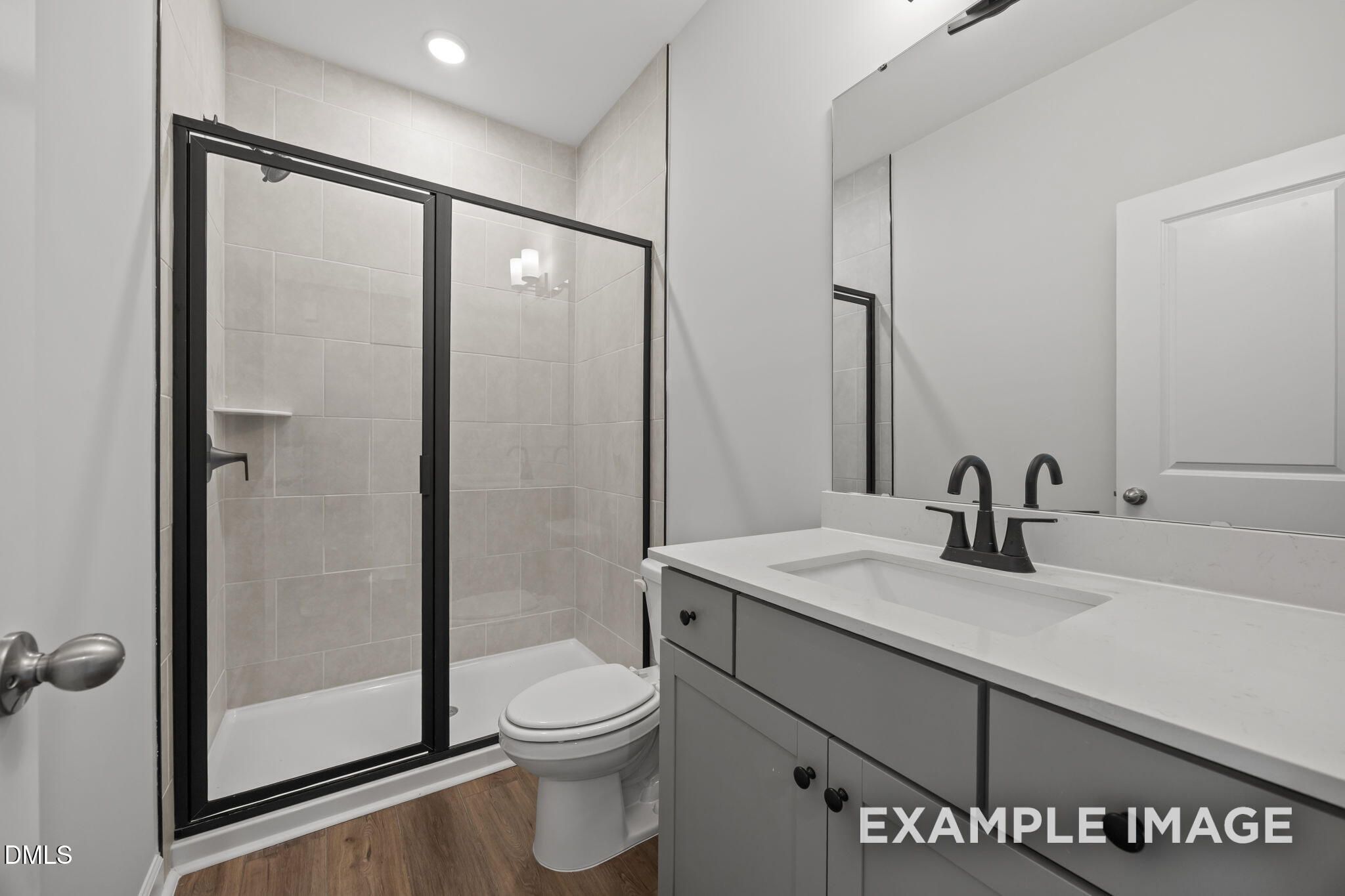 Modern bathroom with glass shower, gray vanity, and matte black fixtures in The Beech floor plan by Davidson Homes, Wendell Ridge NC