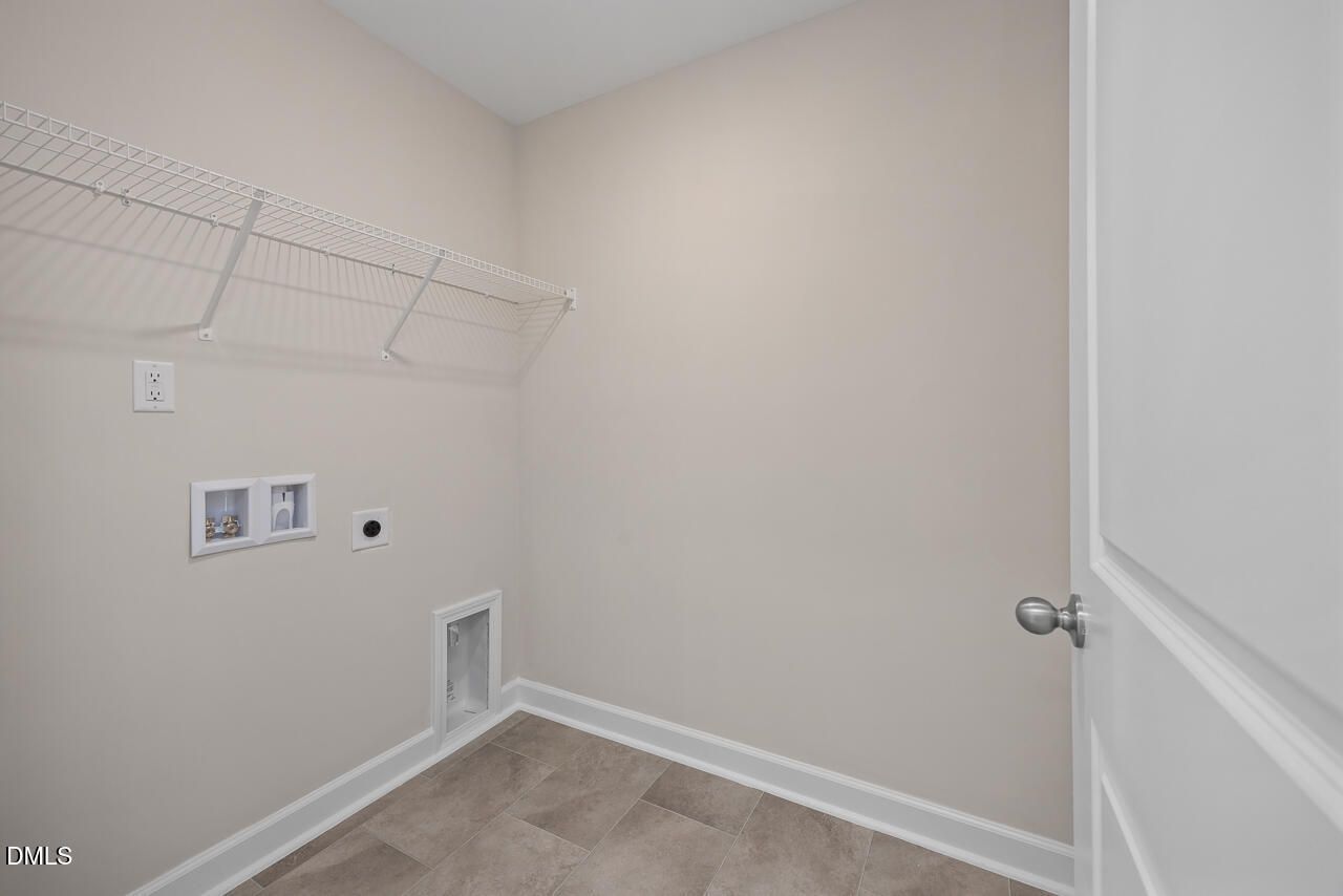 Spacious laundry room with wire shelving, washer-dryer hookups and beige walls in Davidson Homes The Graham, Fuquay-Varina, NC
