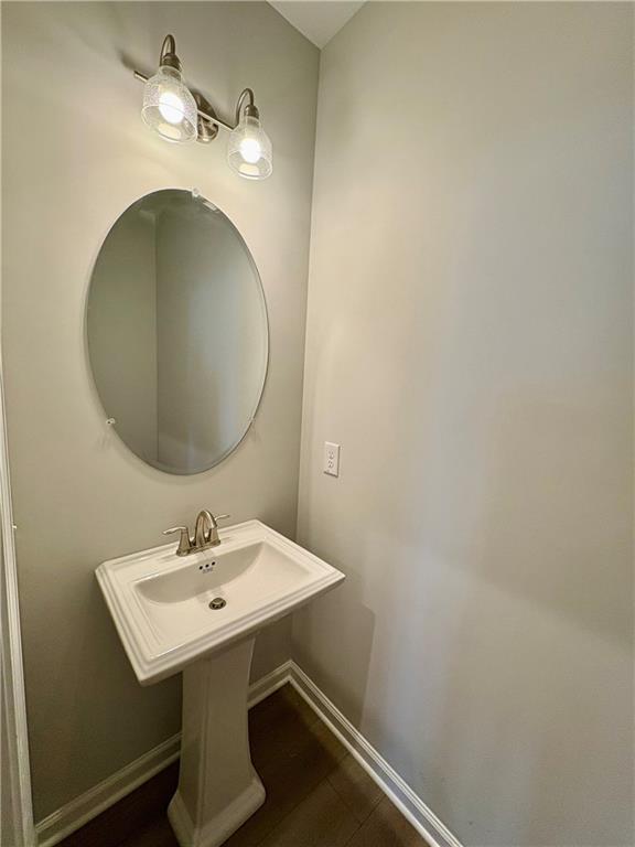 Elegant powder room with white pedestal sink, oval mirror, and sconce lights in light gray tones, The Monroe A, Davidson Homes Emerson GA