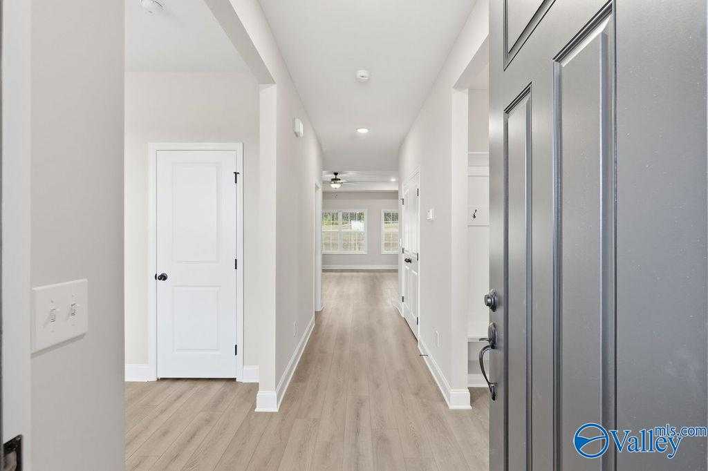 Spacious entry hallway with light wood floors, white doors, and ceiling fan in Davidson Homes The Rockford B, Hartselle, Alabama