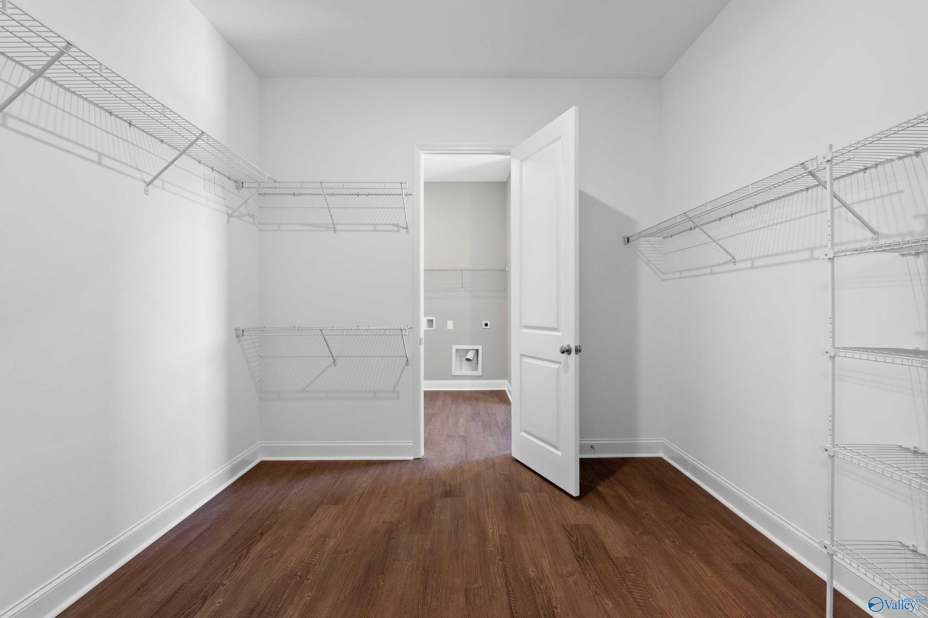 Spacious walk-in closet with white wire shelving and adjacent laundry in Davidson Homes The Arcadia, Huntsville AL