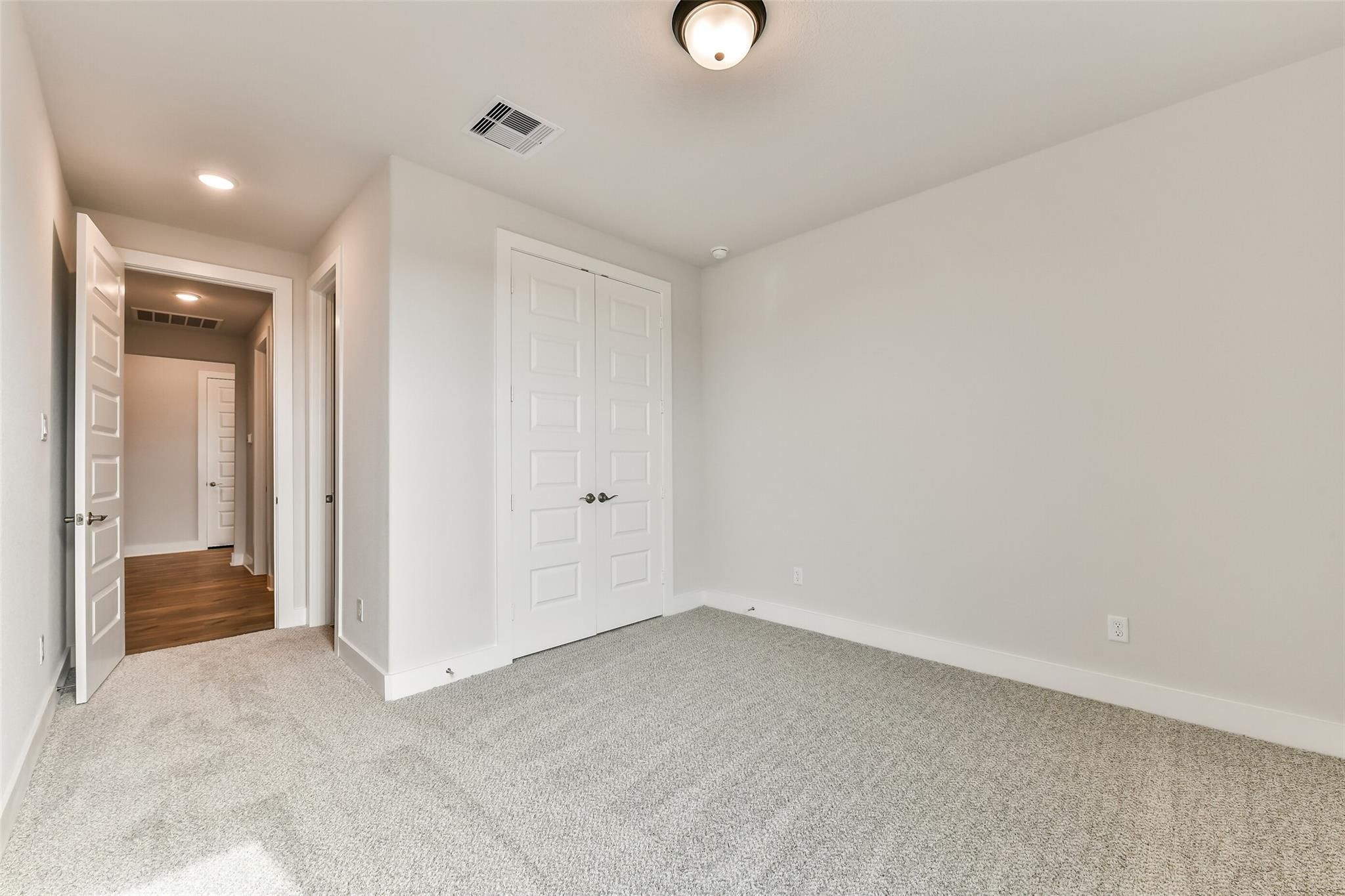 Spacious secondary bedroom with gray carpet, white walls, and open doors to bathroom in Davidson Homes The George A, Lago Mar, Texas City
